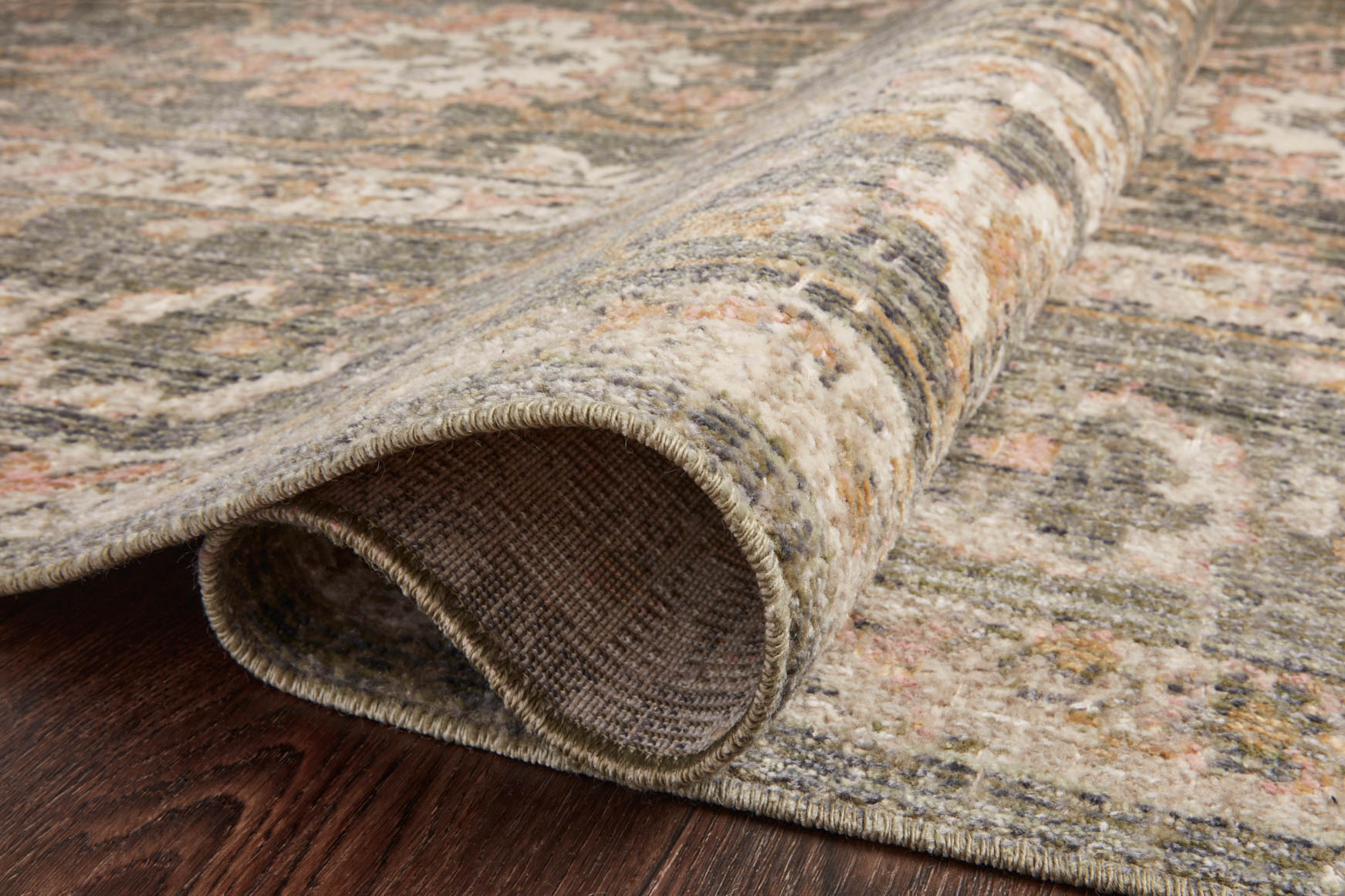 Rolled edge view of sage and blush rug with woven flat pile and border trim.