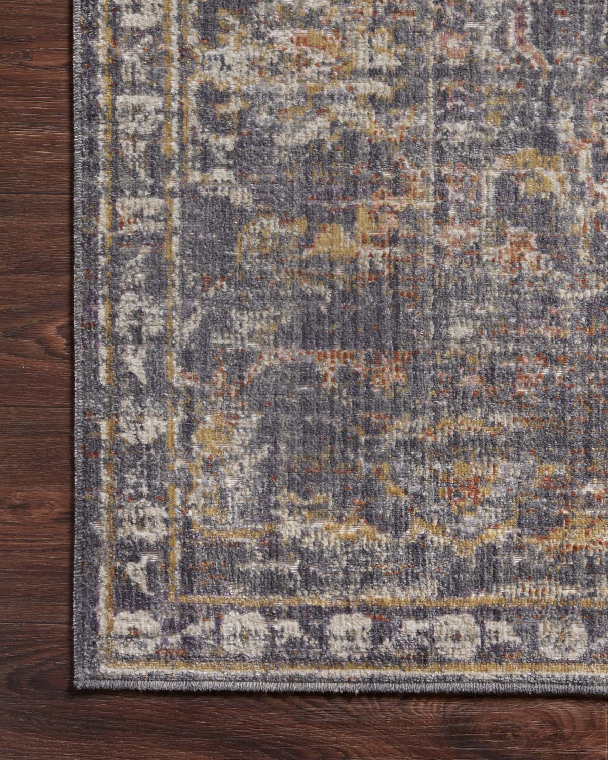 Close-up of graphite rug corner with distressed pattern and woven border edge.