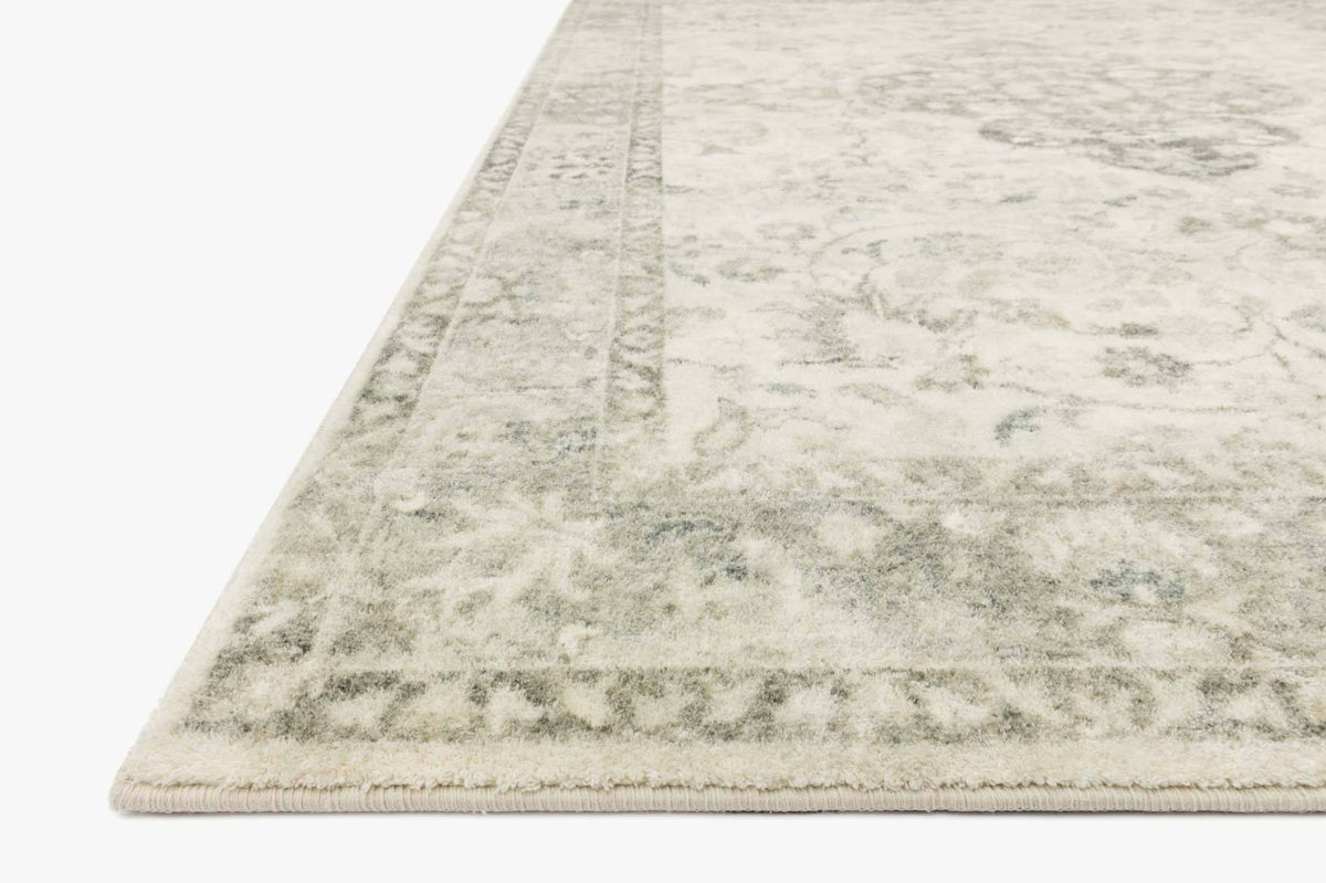 Ivory rug corner with textured silver-gray faded pattern and fringeless edge