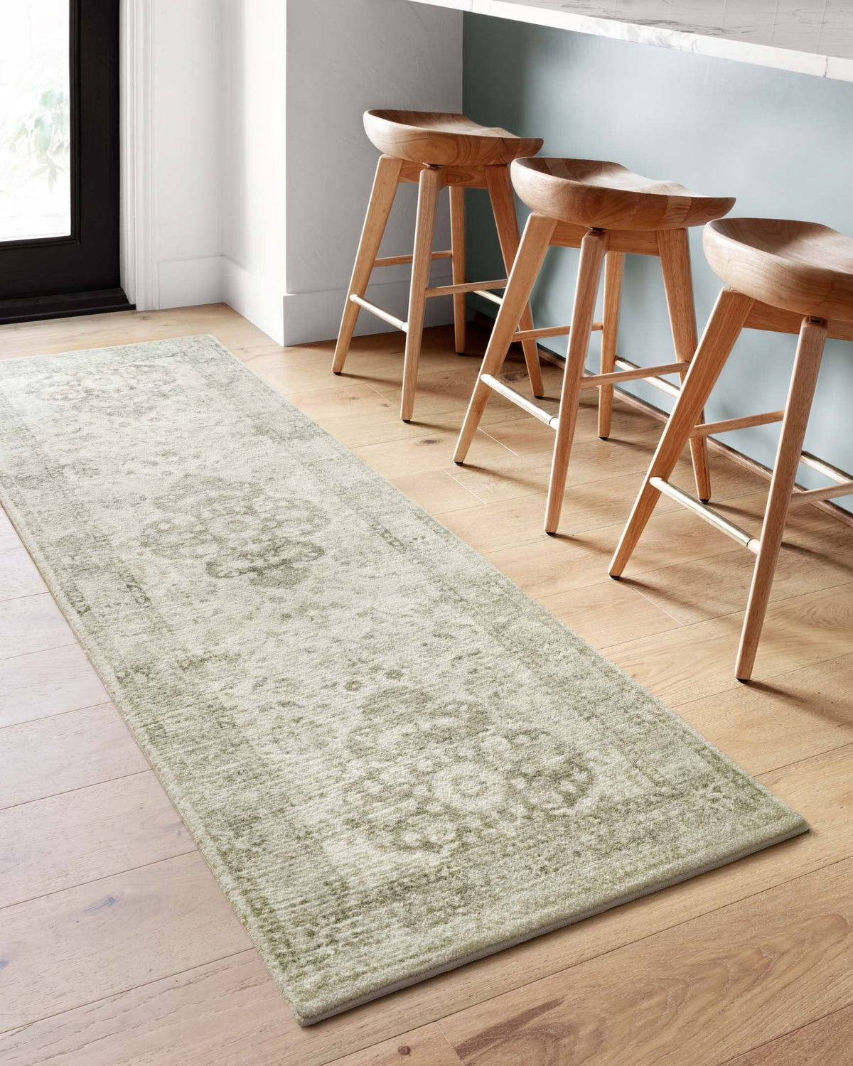 Rectangular ivory rug with light silver distressed floral design near dining chairs