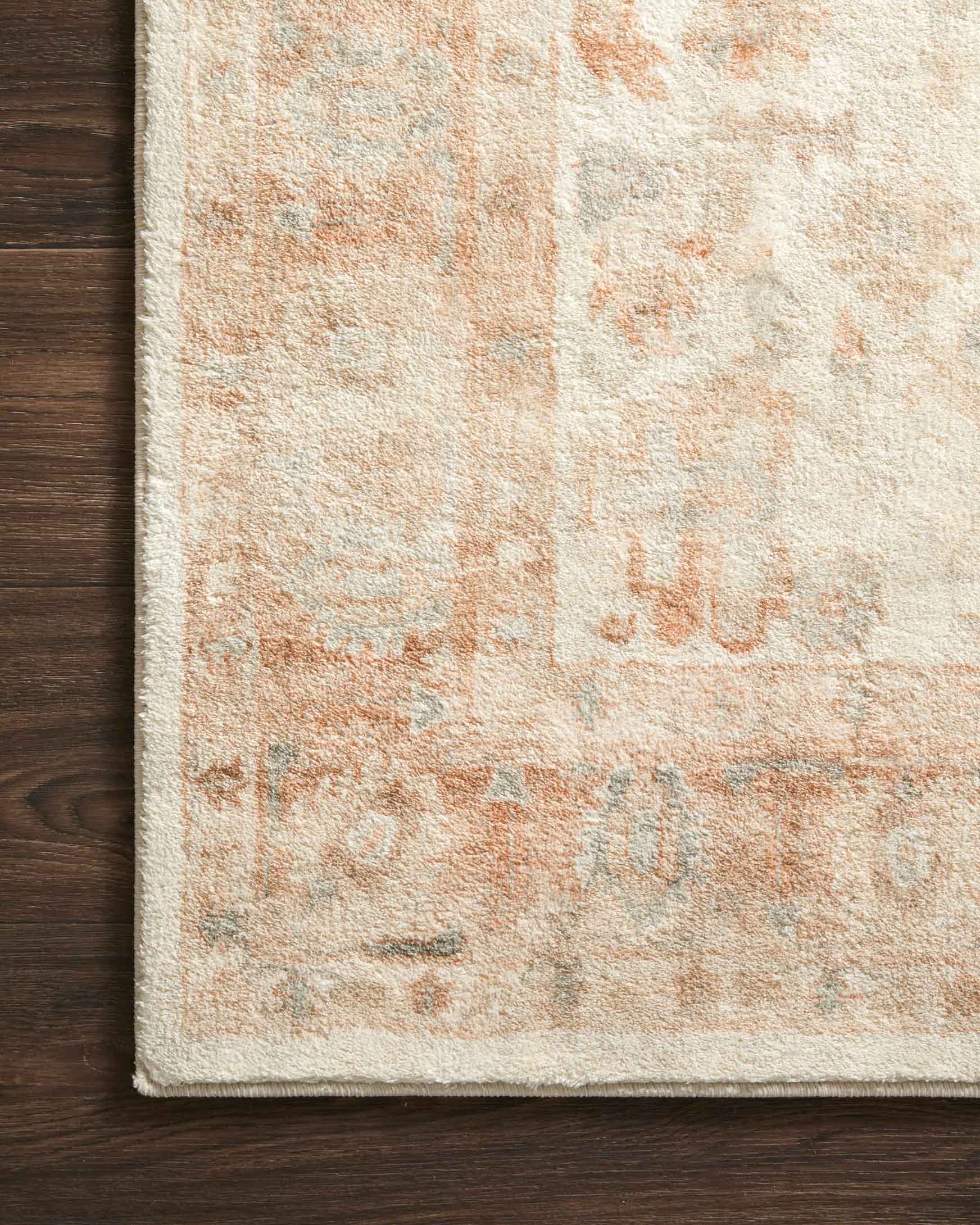 Ivory rug with distressed texture and terracotta medallion motifs, stitched edge