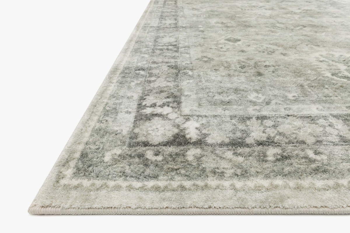 Steel-gray rug corner close-up with distressed geometric pattern and bound edge
