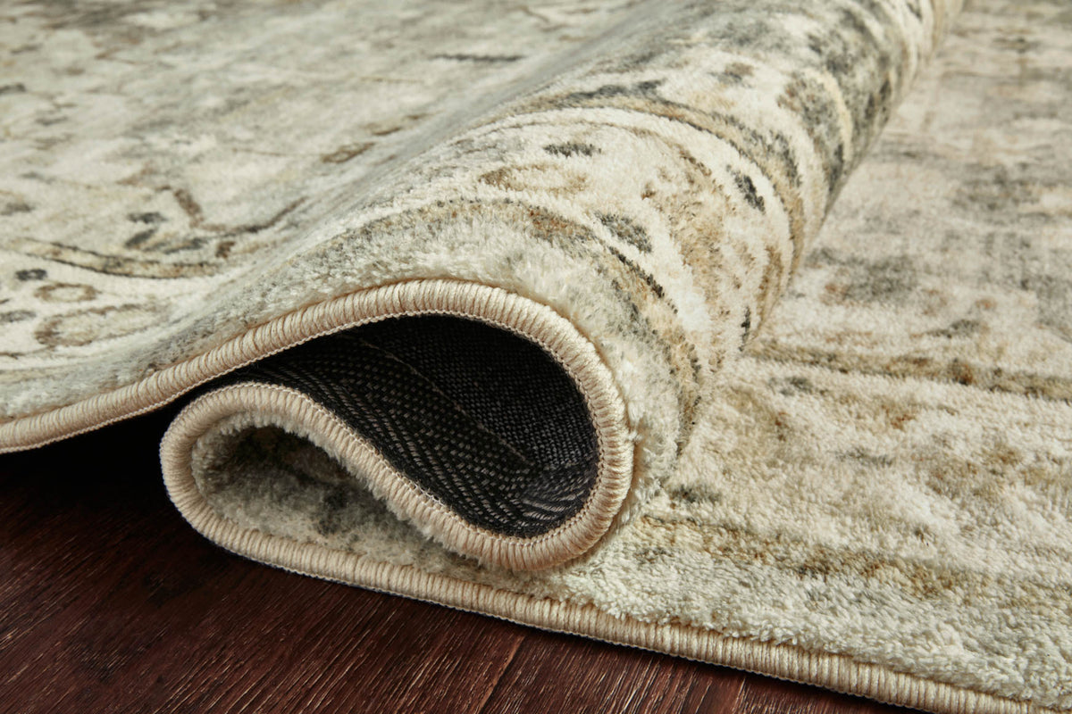 Close-up of sage and beige rug edge with light binding and dark backing.