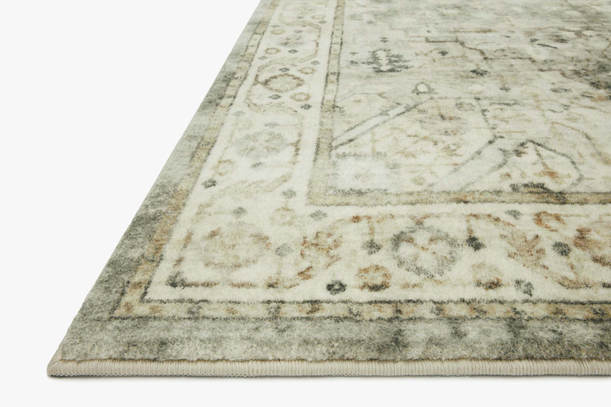 Corner view of sage and beige traditional rug with distressed panel pattern.
