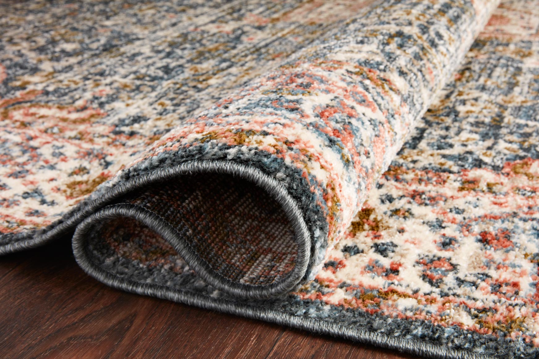 Rug edge close-up with dark bound backing and blue-and-cream distressed pattern