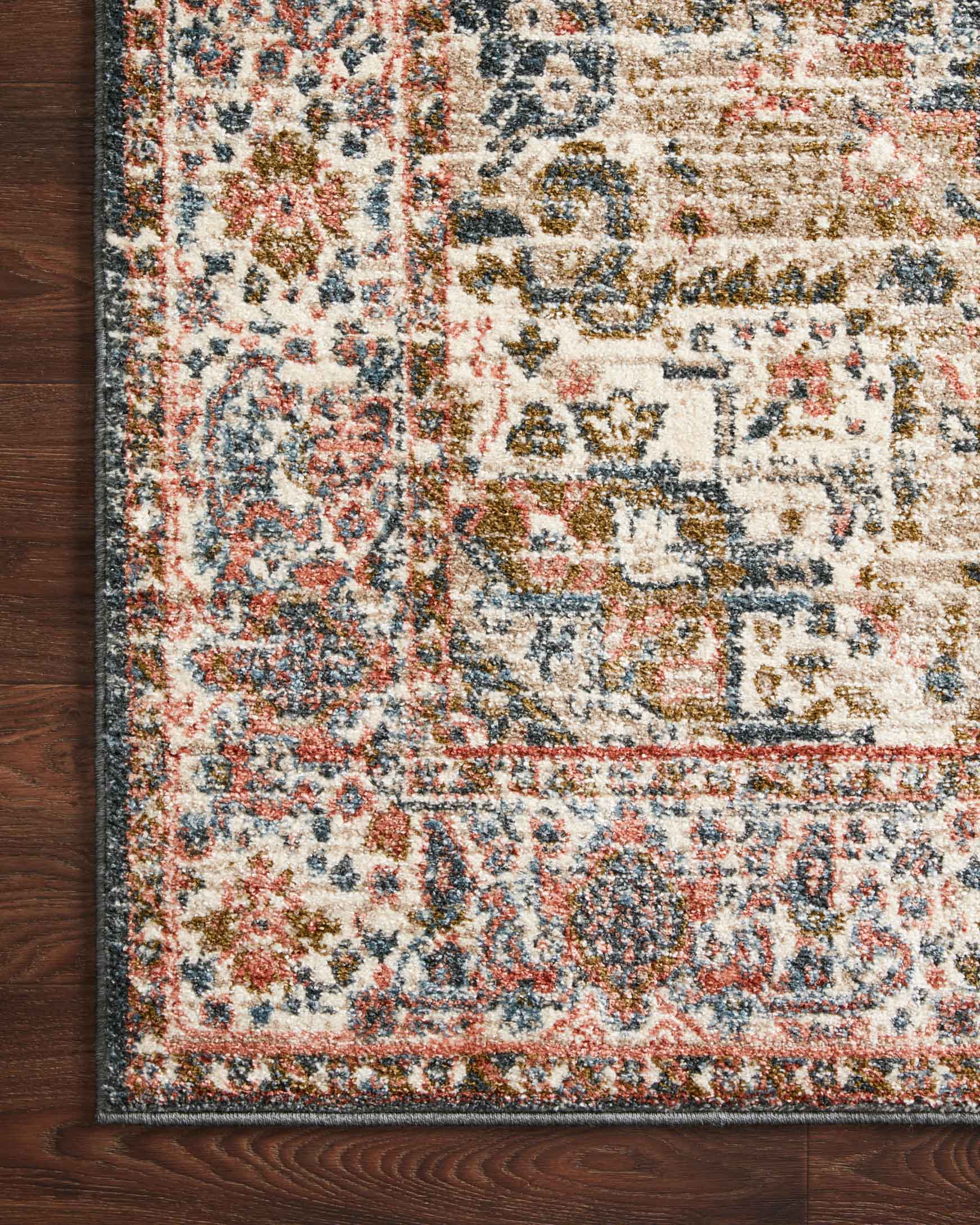 Rug corner detail with blue, cream, and rust geometric border and faded motifs