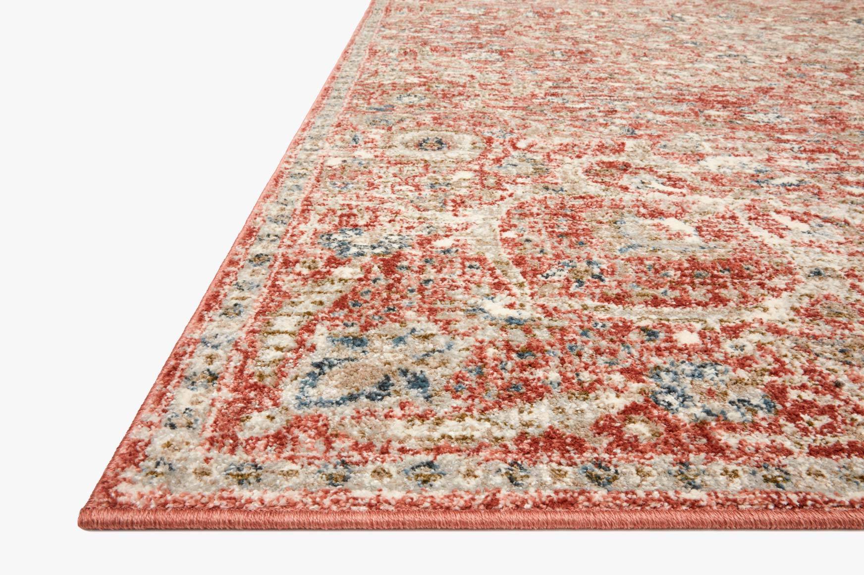 Rust and beige area rug corner with distressed pattern and short fringed edge