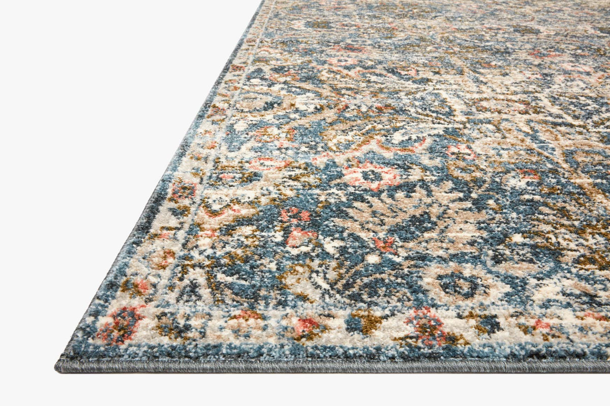 Rectangular blue-and-sand rug with faded ornate motif pattern, angled view