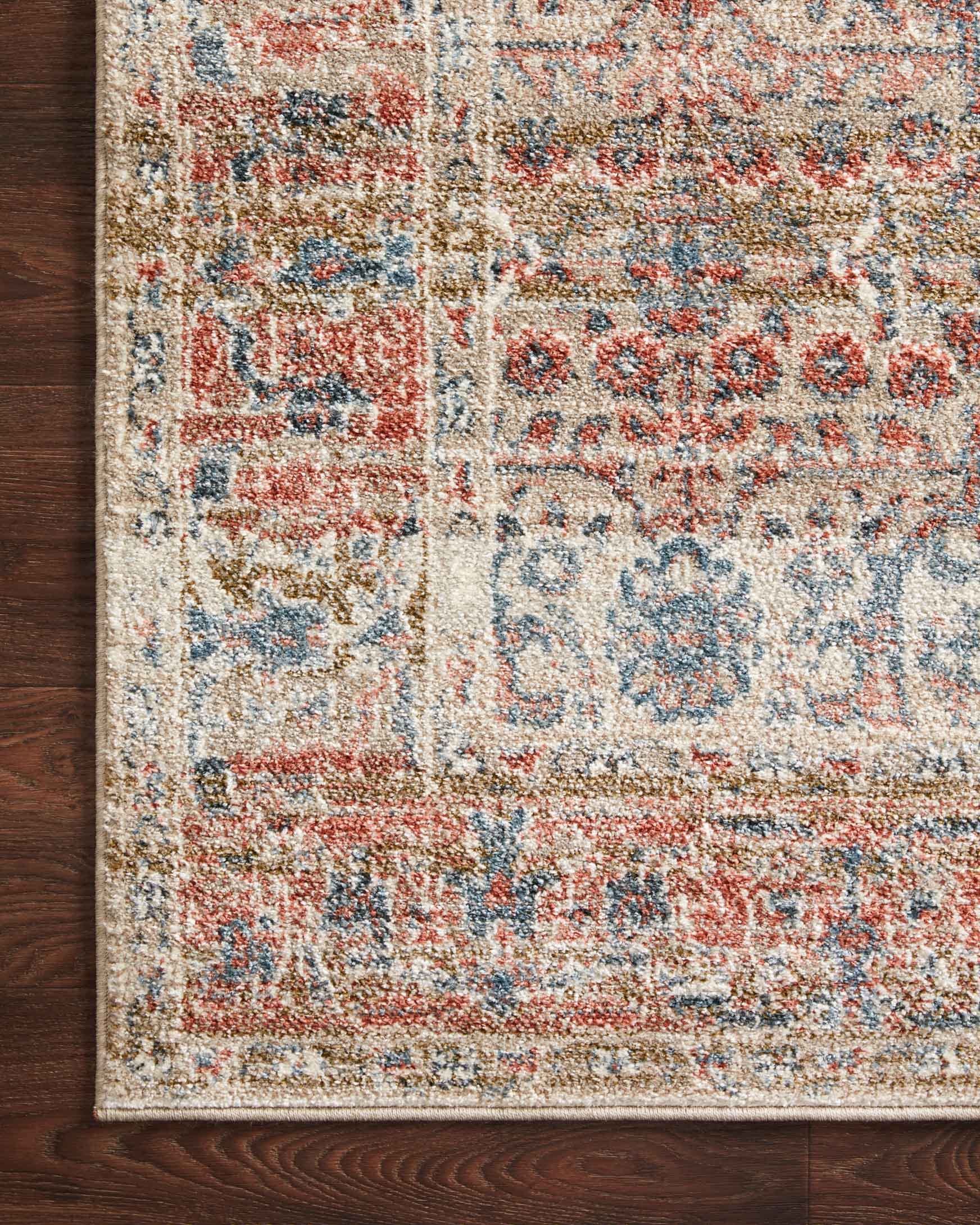 Sand rug close-up on hardwood floor, rust and blue geometric motifs with border