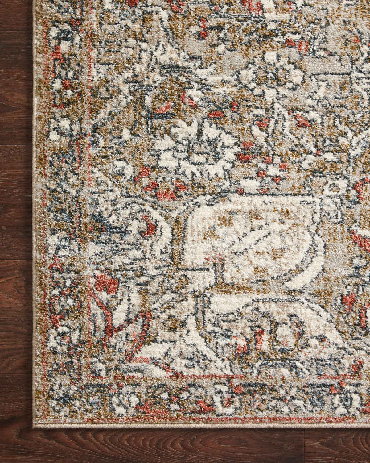 Corner close-up of beige, blue-gray, and rust vintage area rug with ornamental scrollwork.