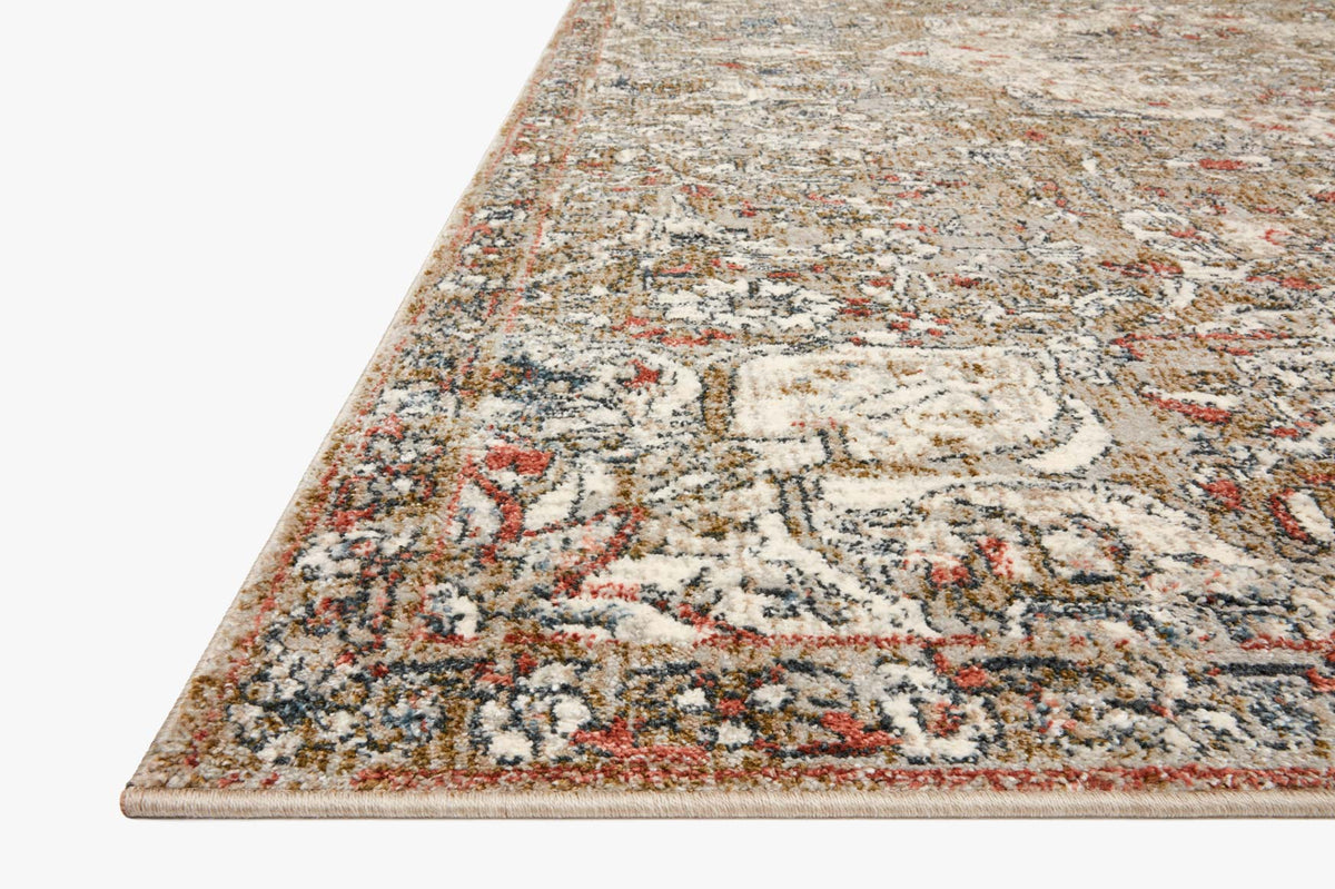 Close-up of beige rug corner with faded ornate motifs and speckled texture