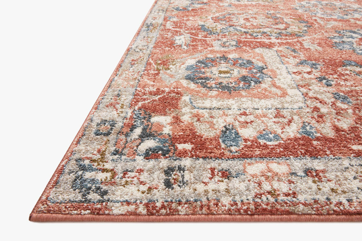 Rust, cream, and blue distressed rug corner with ornate floral medallion.