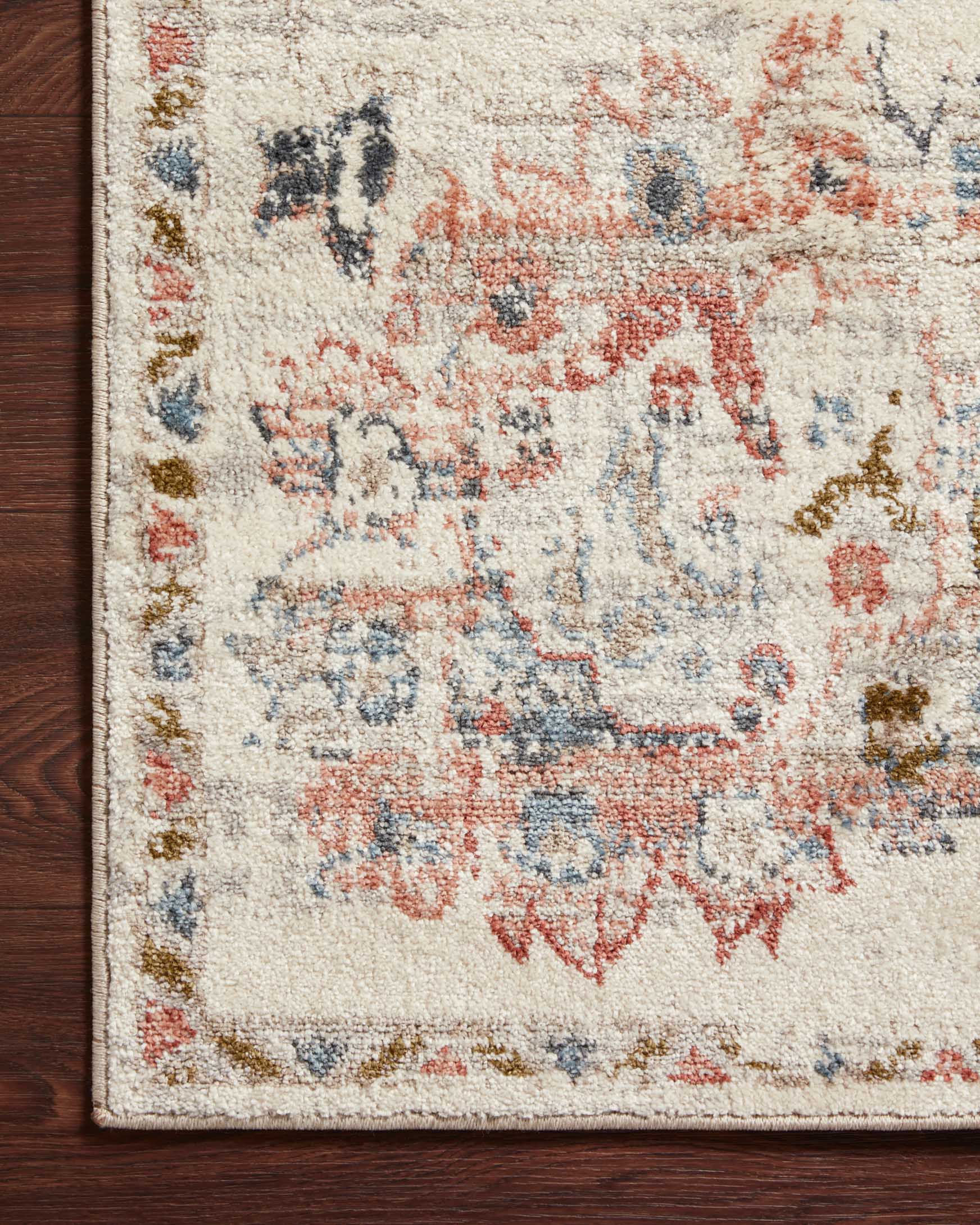 Corner detail of ivory rug showing multicolor pattern and rug edge binding