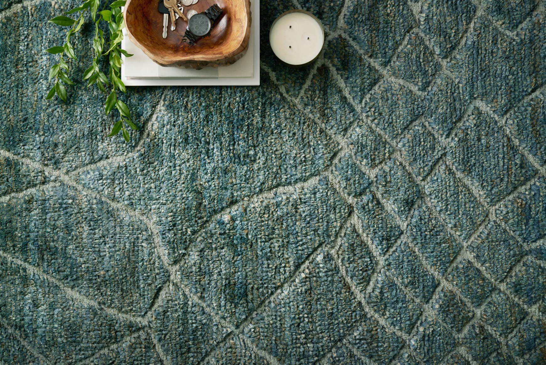 Close-up of teal hand-knotted rug texture with white diamond lattice pattern