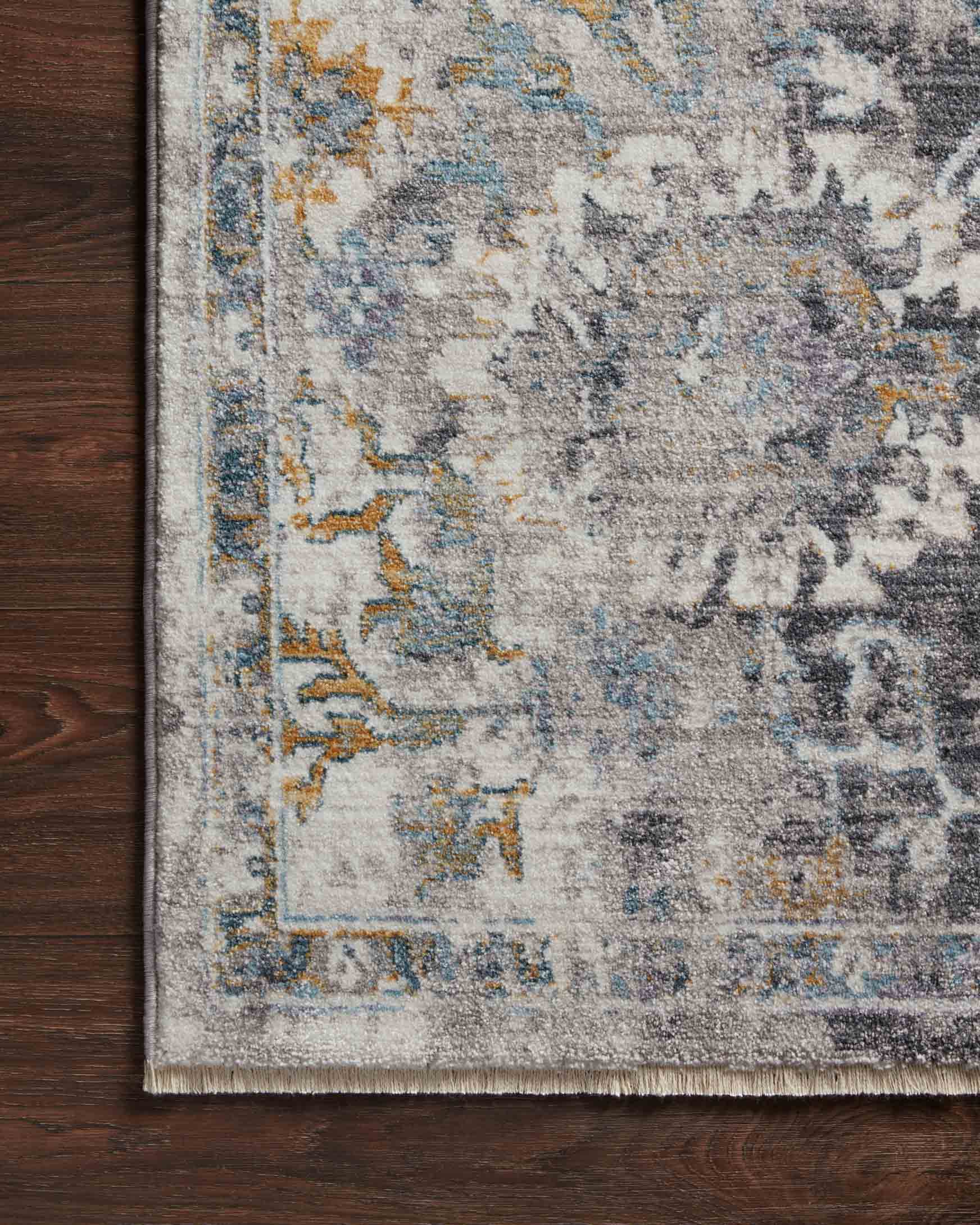 Grey rug with blue and gold distressed design and woven border along the edge