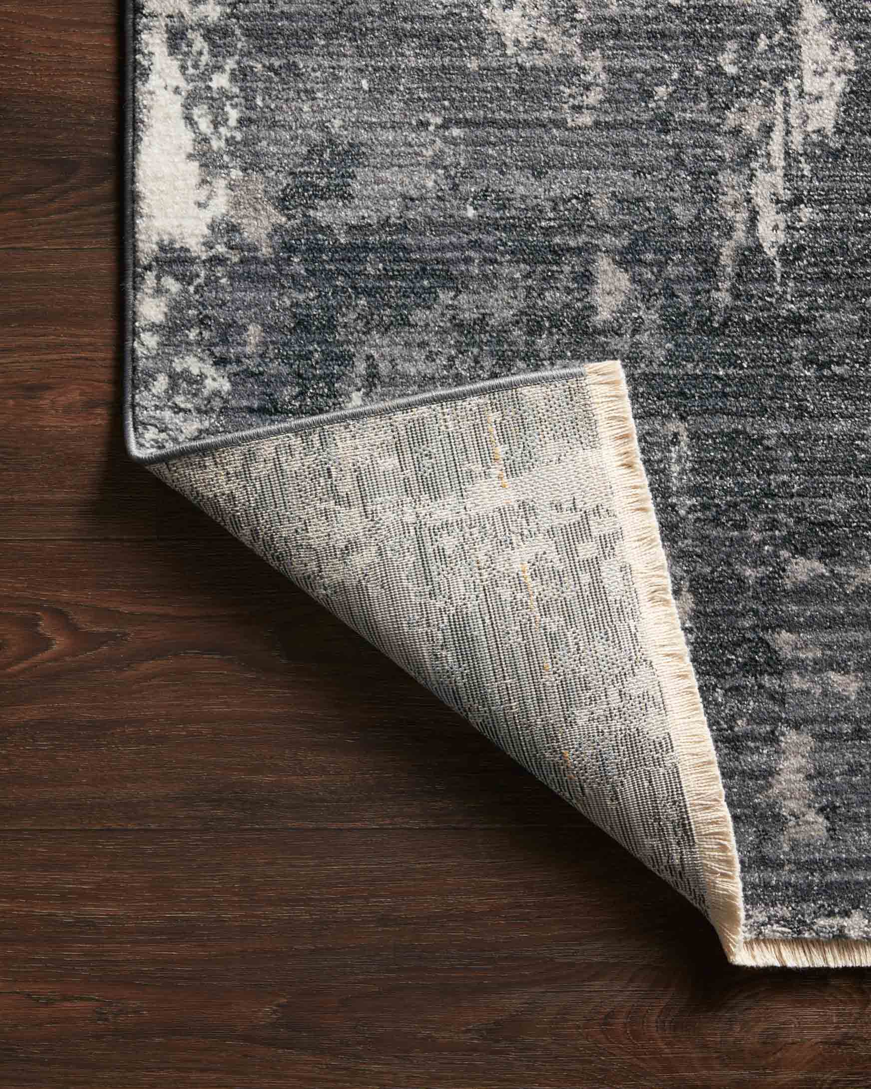 Charcoal and silver rug corner with patterned underside and stitched border