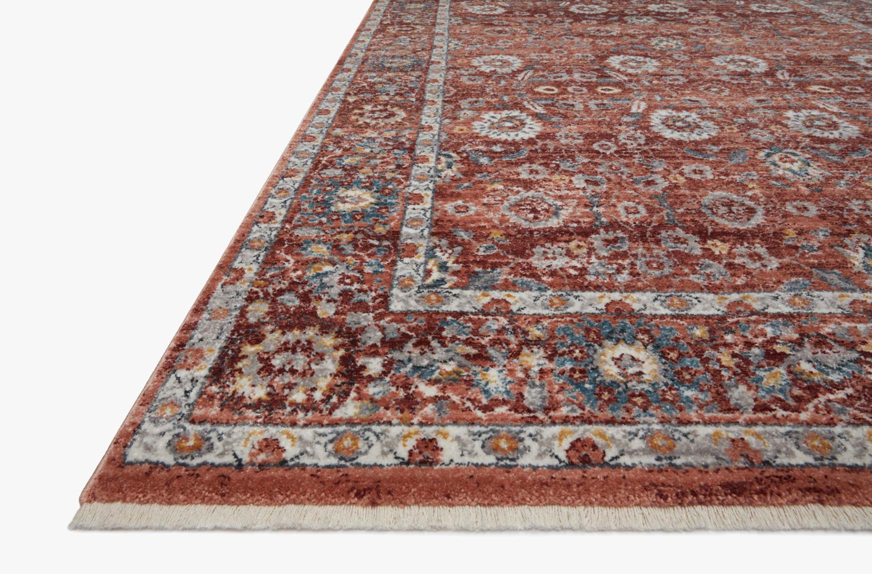 Corner view of brick red rug with distressed medallion pattern and detailed border