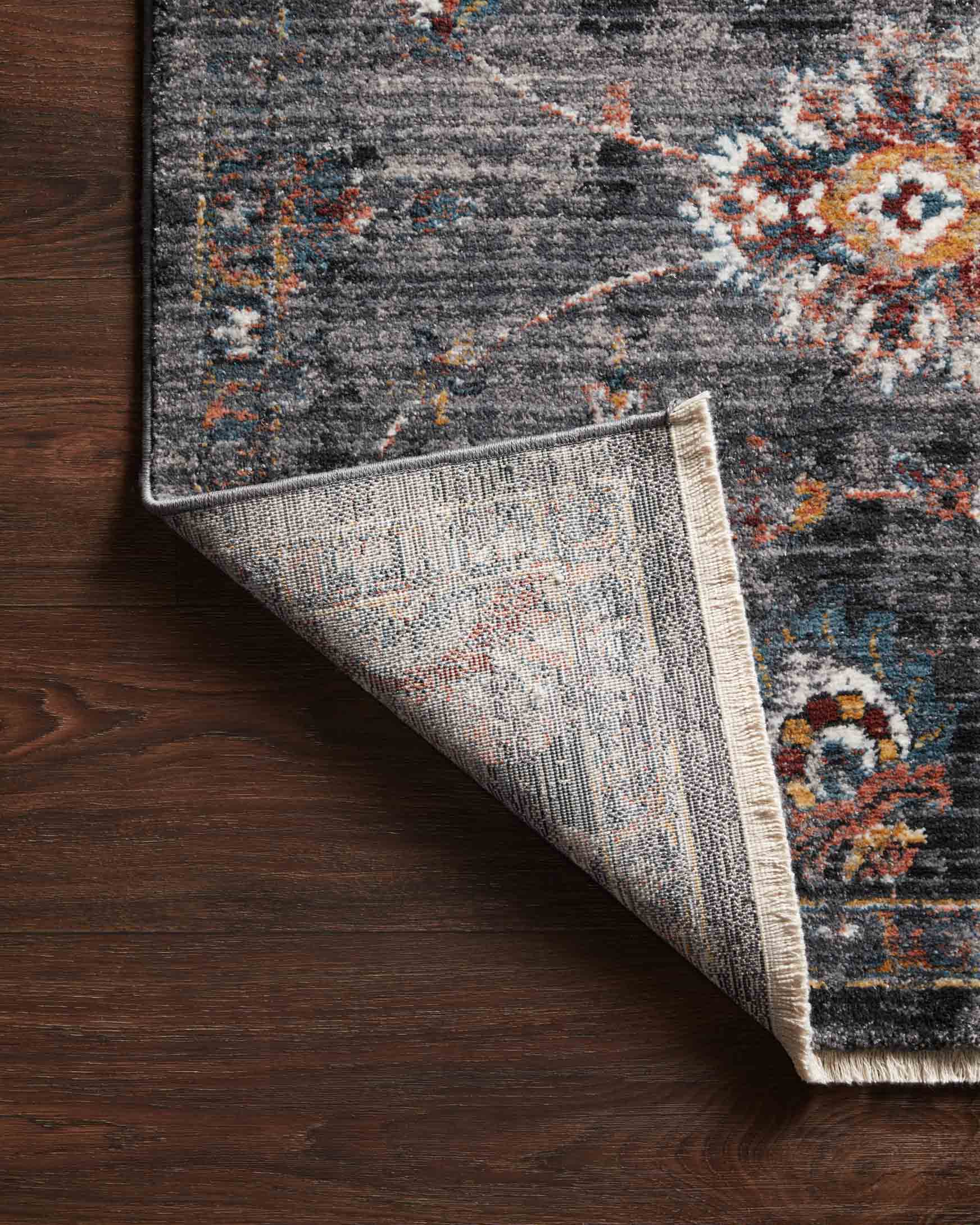 Corner detail of charcoal power-loomed rug showing lighter backing and multicolor pattern