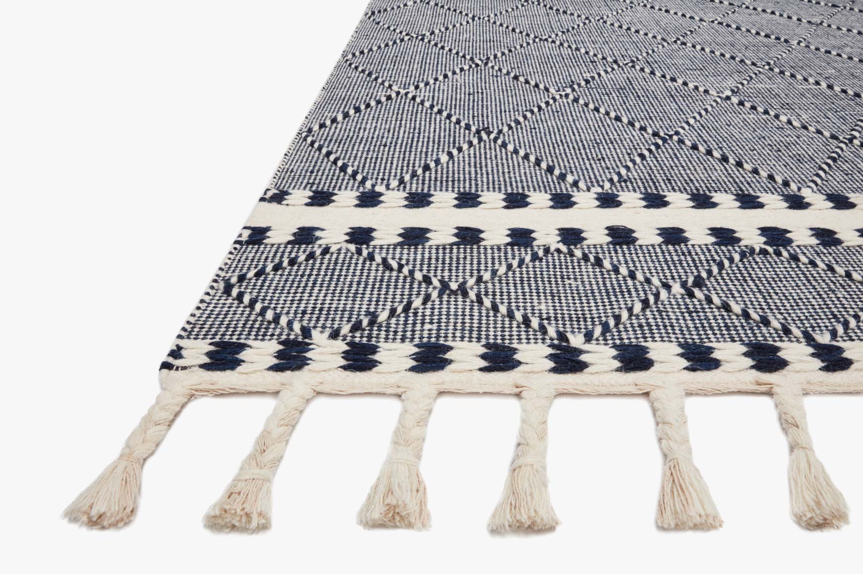 Rug edge with navy diamond motifs and off-white fringe tassels