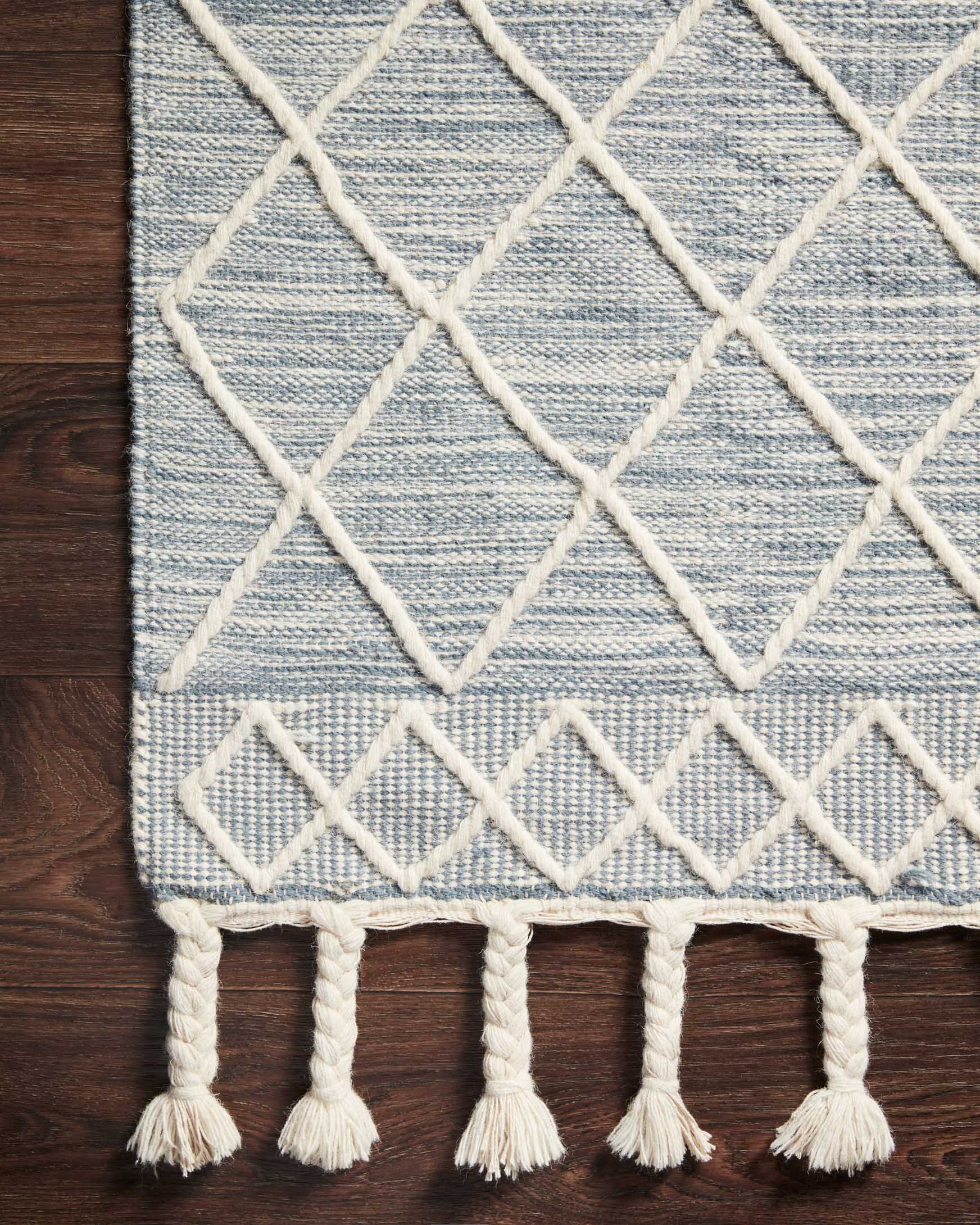 Teal woven rug corner with white lattice pattern and tassel fringe edge