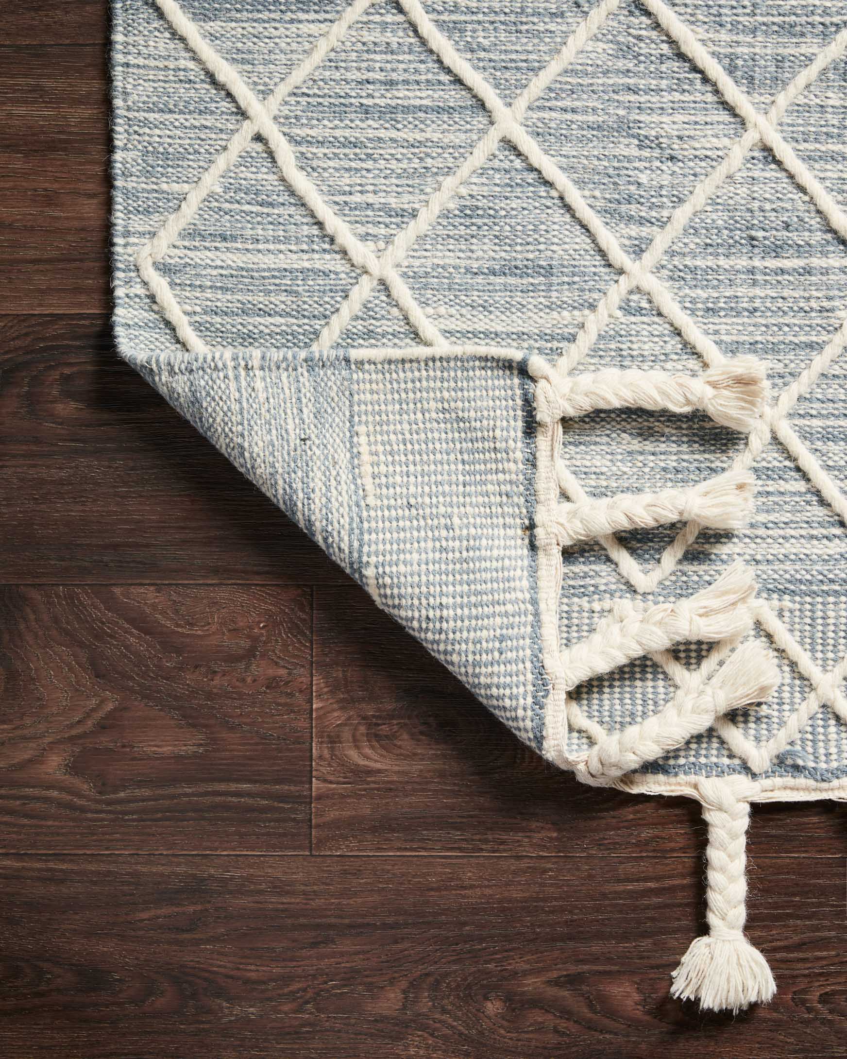 Teal woven rug edge with white geometric lattice and tassel fringe