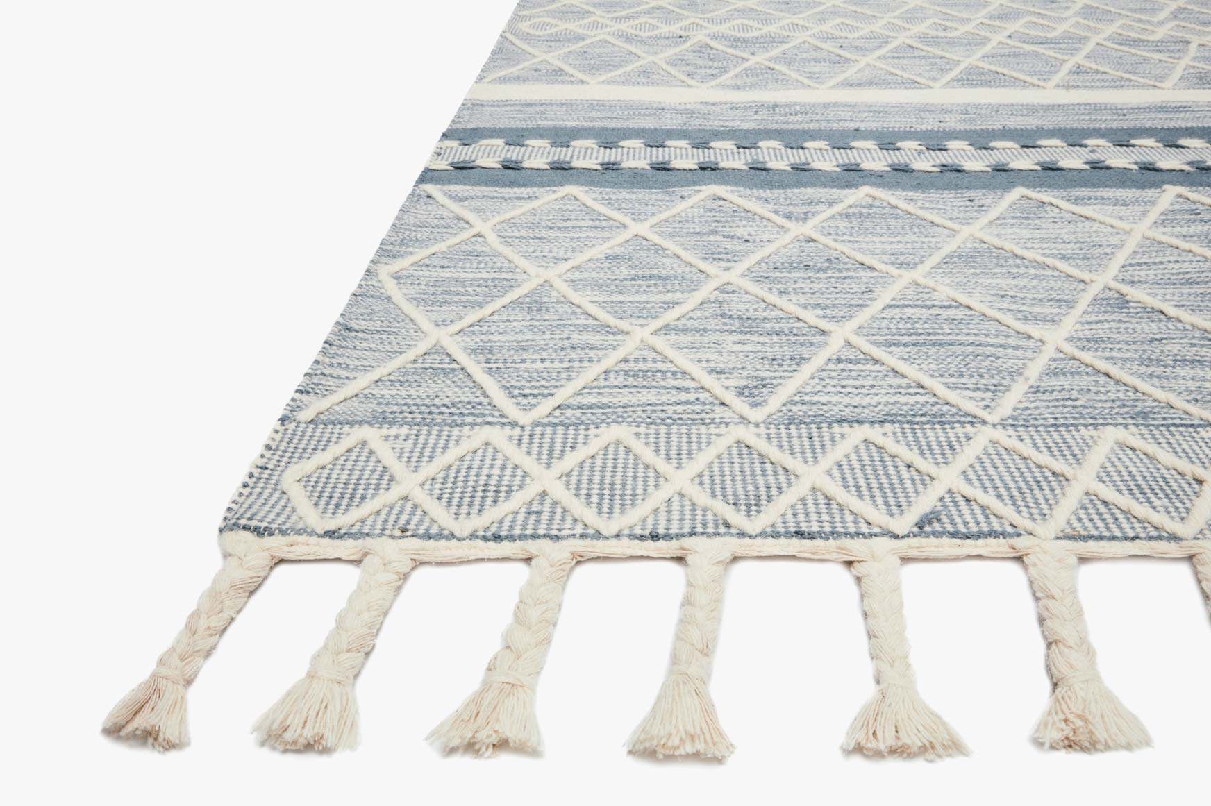 Corner of teal rug with white diamond lattice and tassel fringe