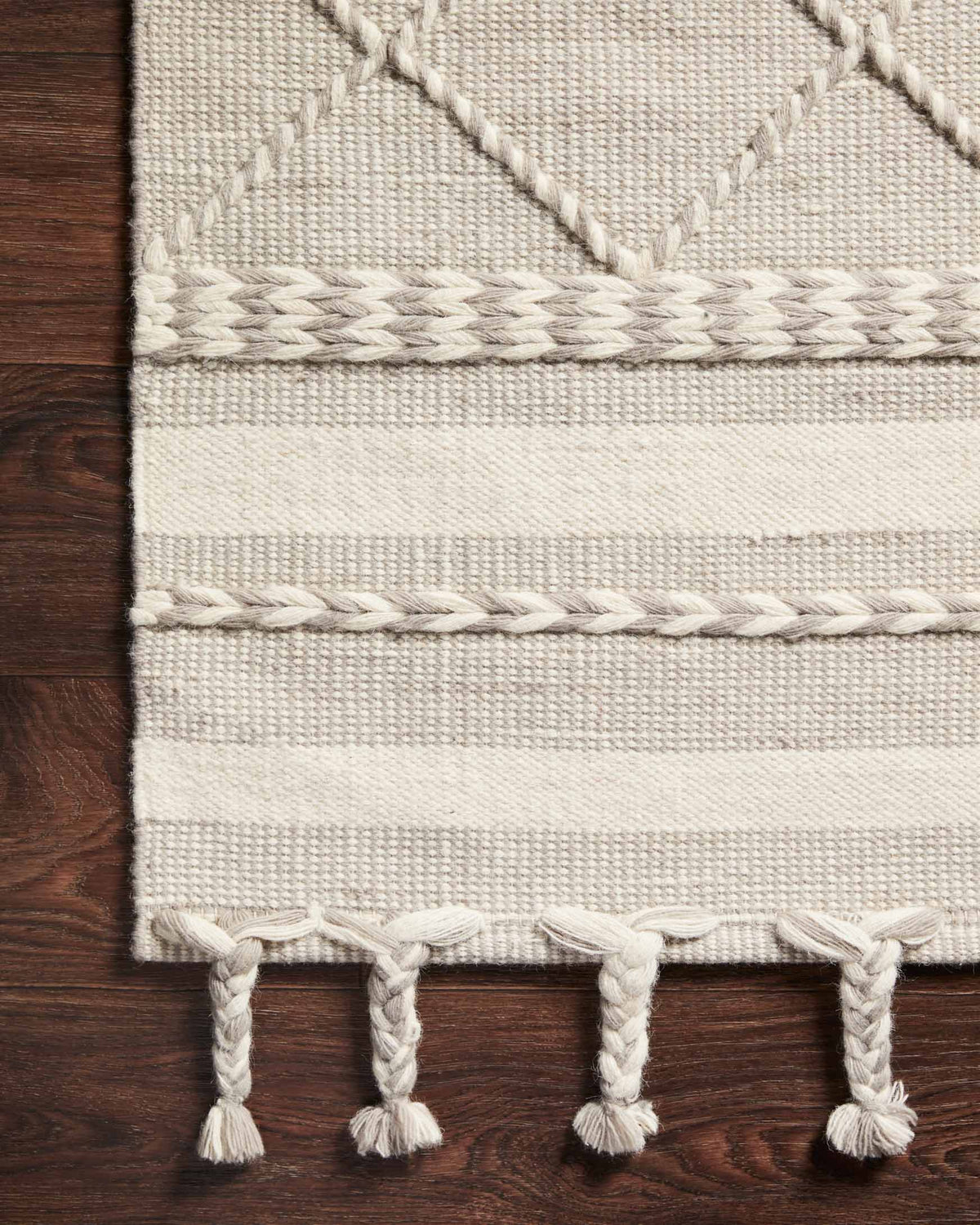 Close-up of silver rug border with woven stripes and braided fringe tassels