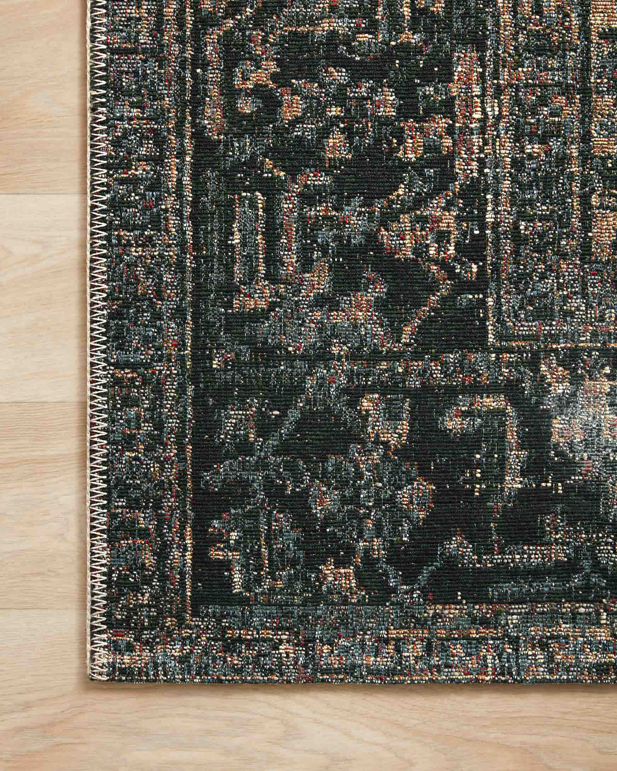 Edge close-up of blue and dark navy rug showing stitched border and multicolor pattern flecks