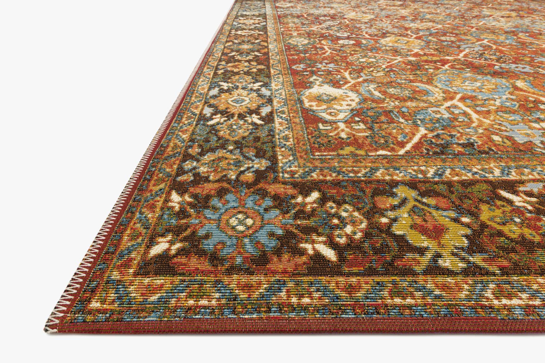 Corner view of red and teal ornate rug with detailed motifs and fringed edges