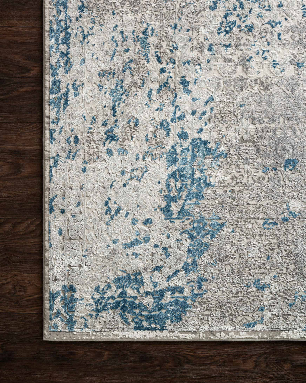 Contemporary distressed rug in light dove with blue abstract pattern along rug edge.