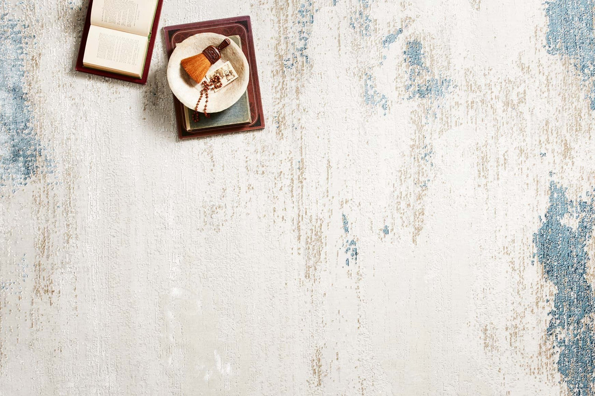Abstract sand-and-ocean rug with blue mottled texture on an off-white ground