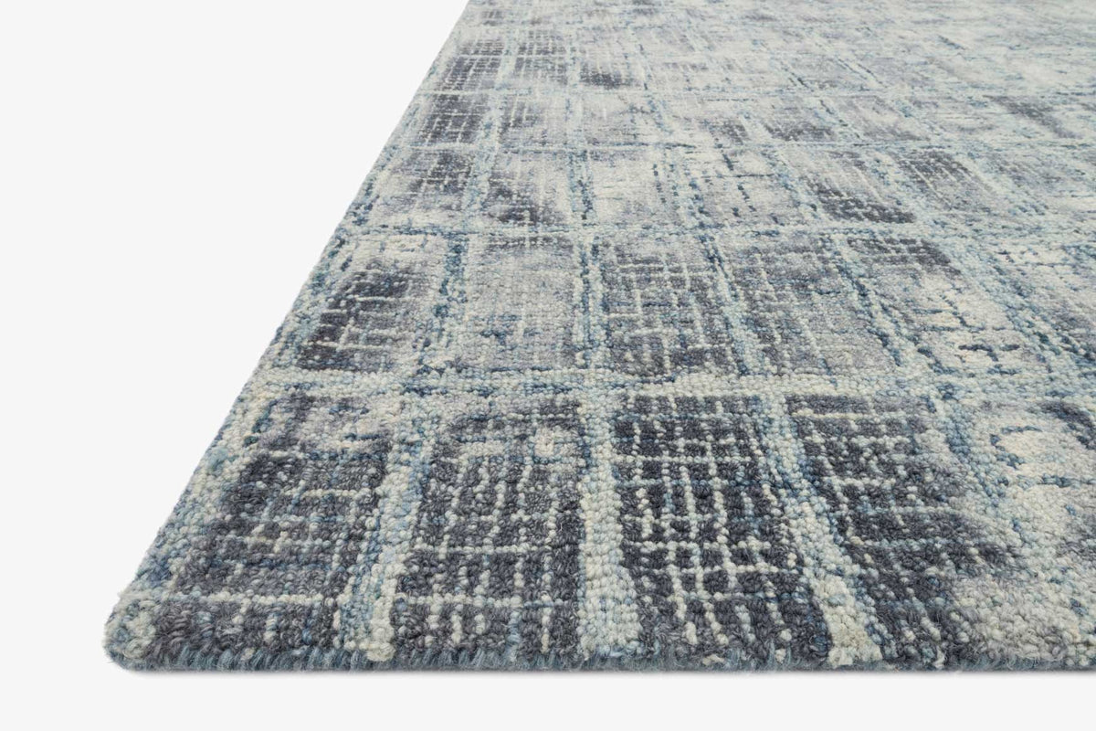 Blue abstract hooked rug with textured grid pattern in a close-up corner view