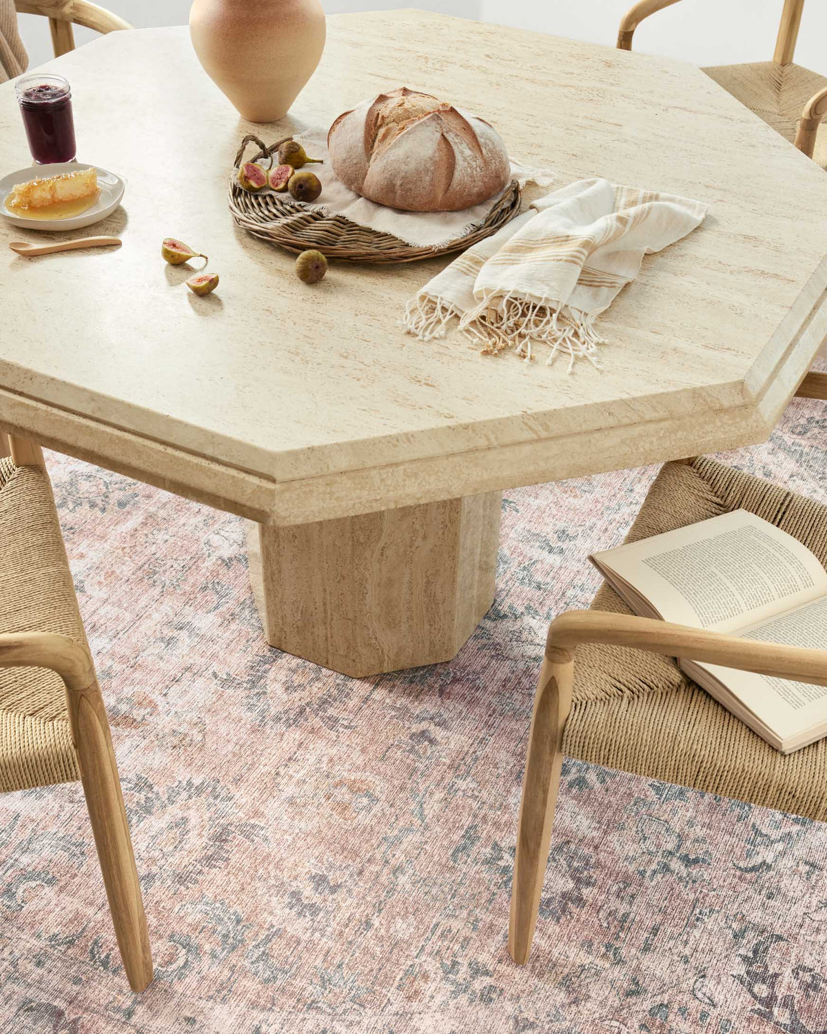 Blush and grey rug with distressed pattern visible beneath dining chair and table.