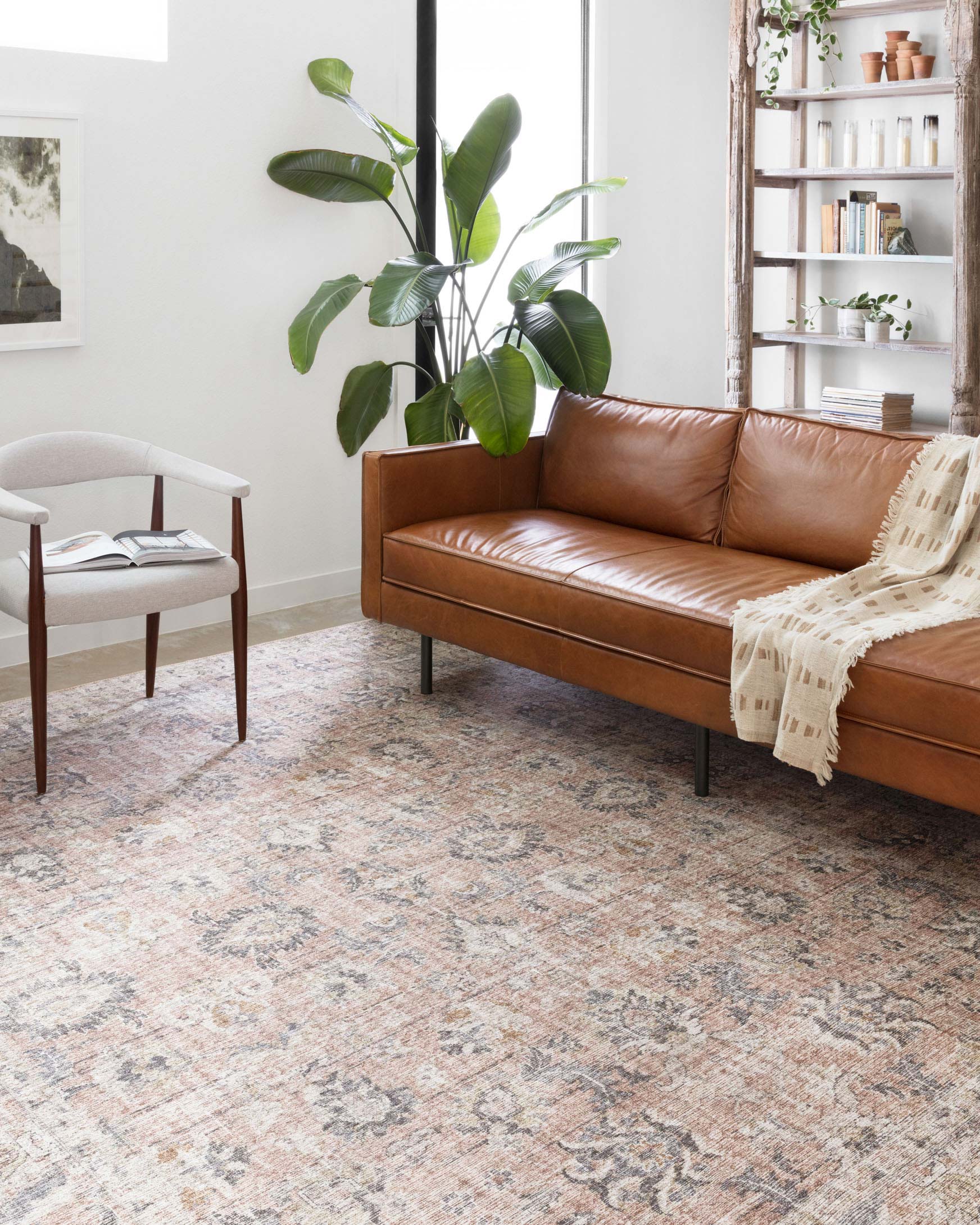 Blush and grey traditional power-loomed rug under a brown leather sofa.