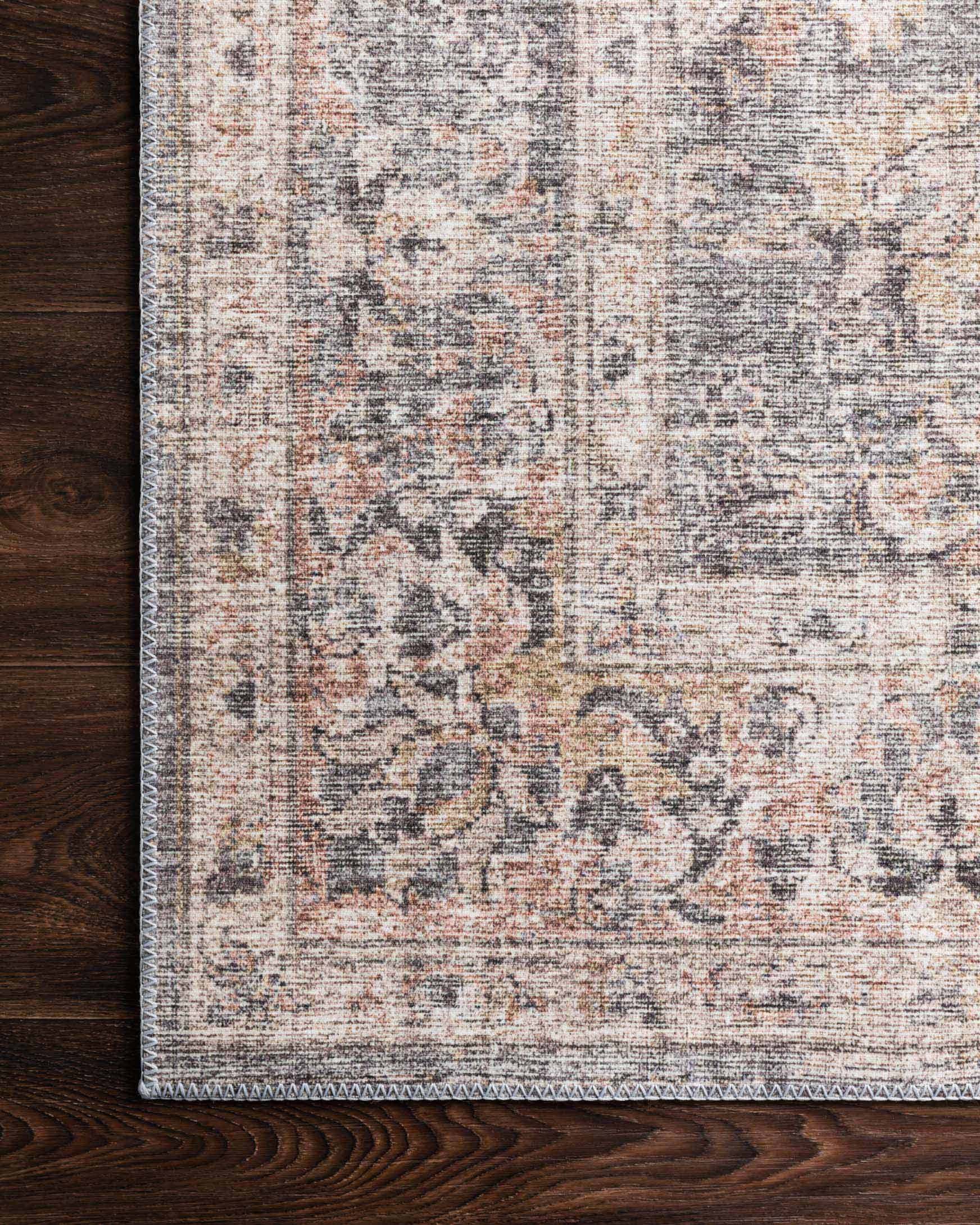 Close-up of grey and apricot rug surface with woven texture and faded motifs