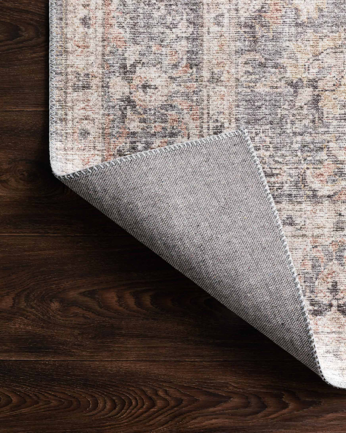Grey and apricot rug corner showing stitched edge and reverse backing