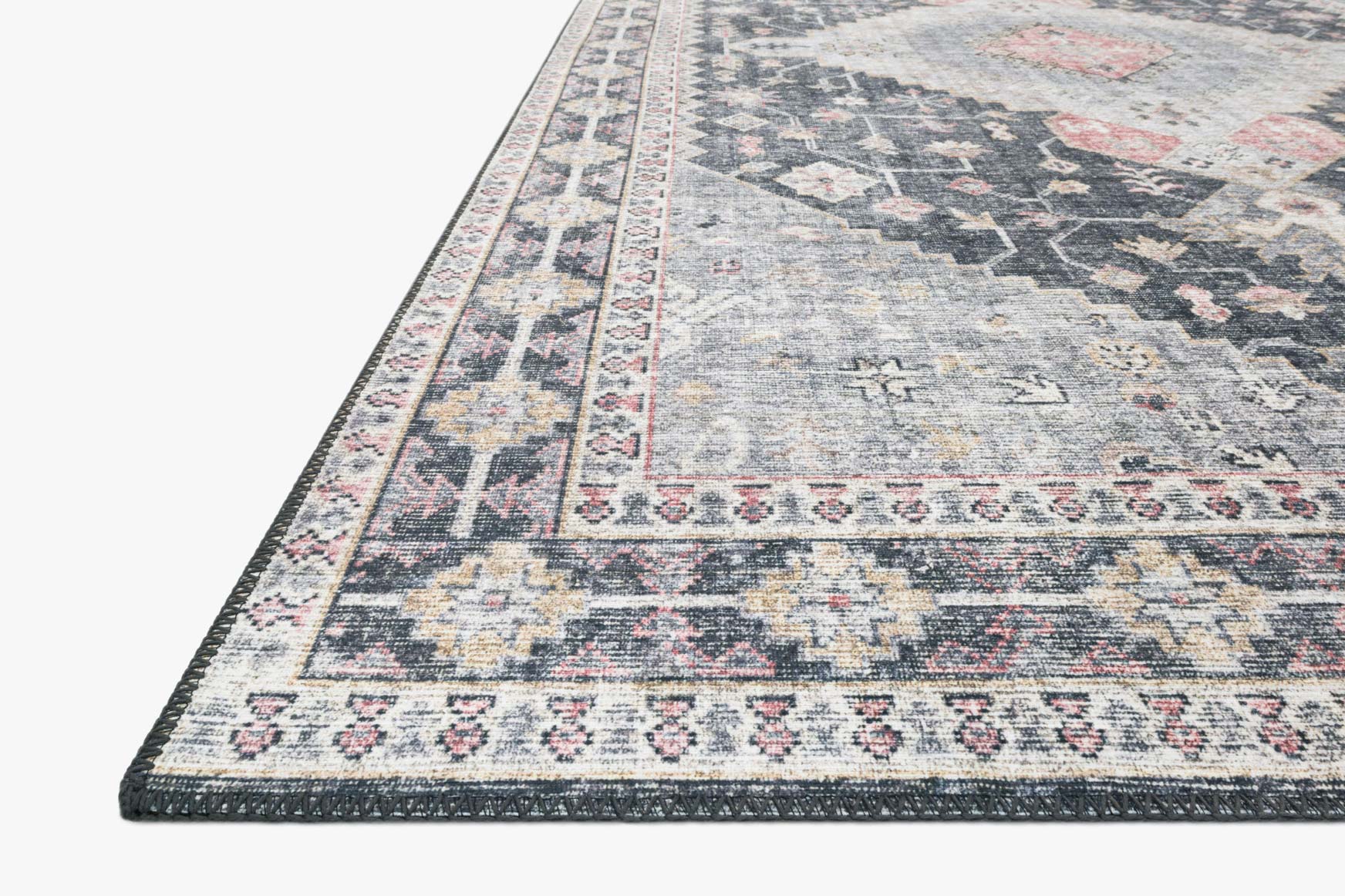 Close-up of traditional gray rug edge with patterned border and diamond motifs