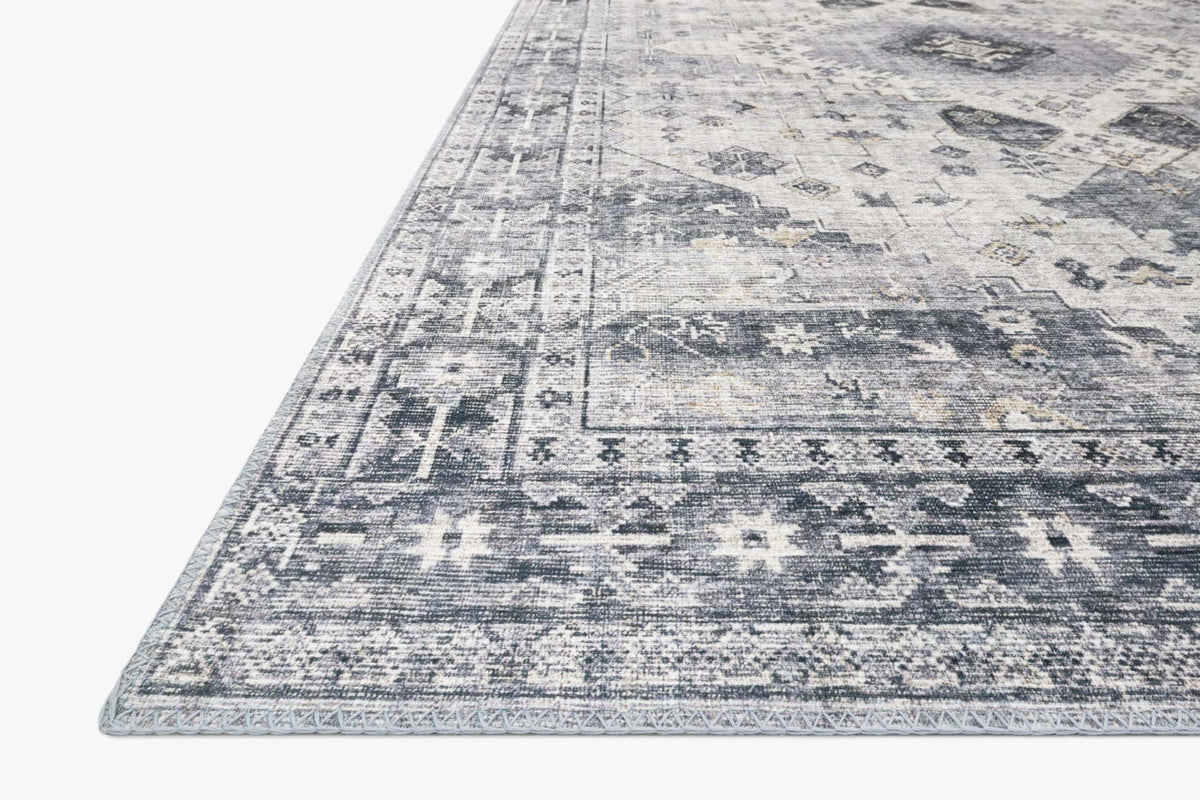 Silver and grey rug corner with distressed geometric blocks and textured border.