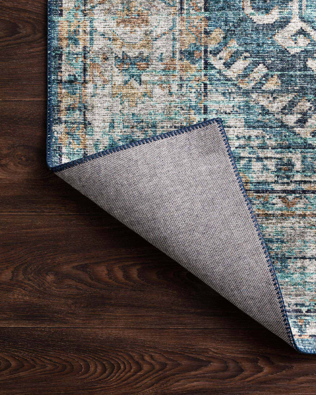 Corner edge detail of denim-blue rug showing woven texture and natural backing