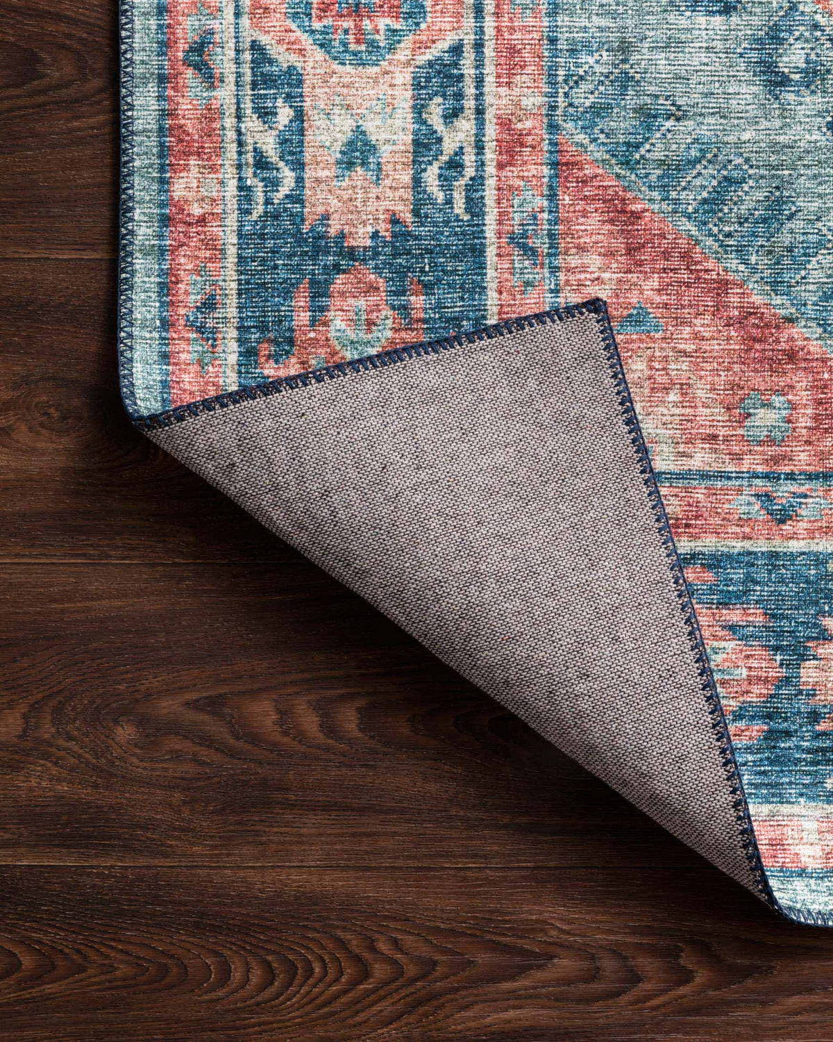 Rug corner detail with underside fabric and border edge on dark wood flooring