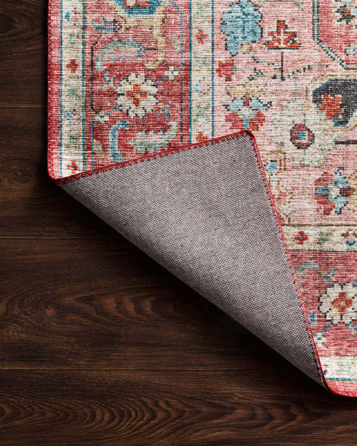 Rolled-back corner of brick and ocean rug showing underside fabric and bound edge