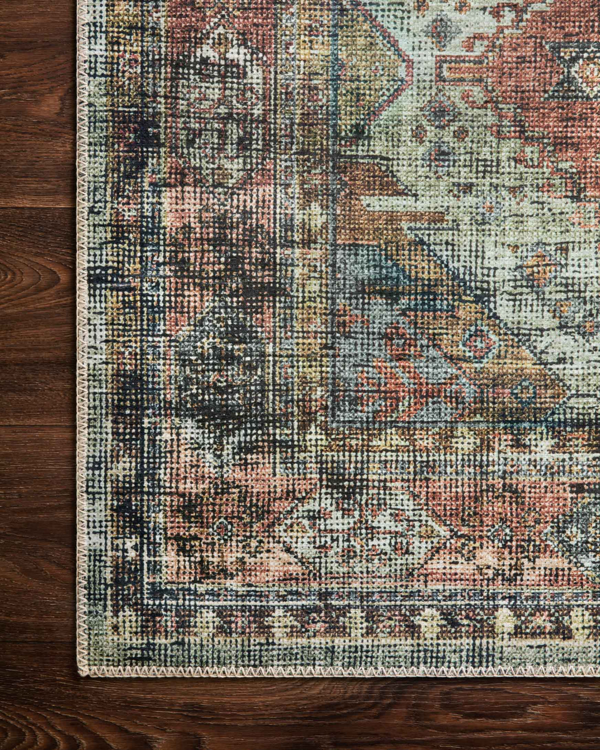 Rug edge close-up showing woven texture and distressed motif, apricot and mist