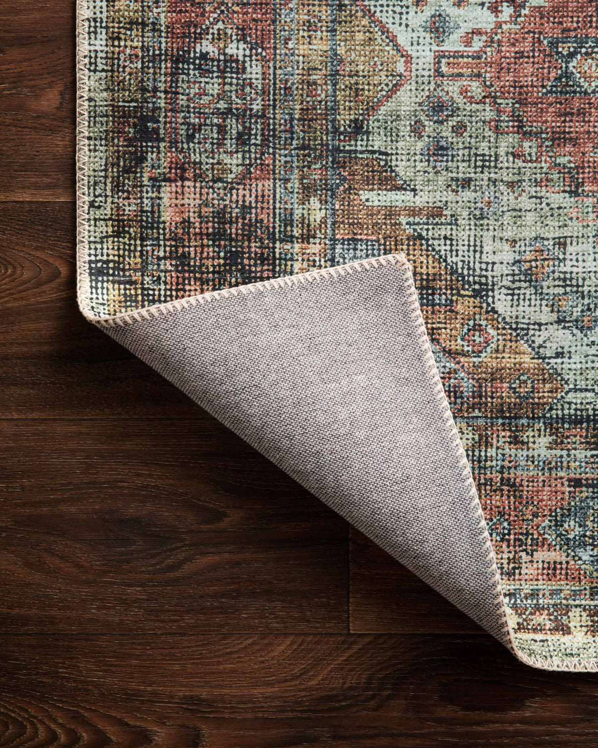 Rug corner detail with braided-look border and folded edge, apricot and mist