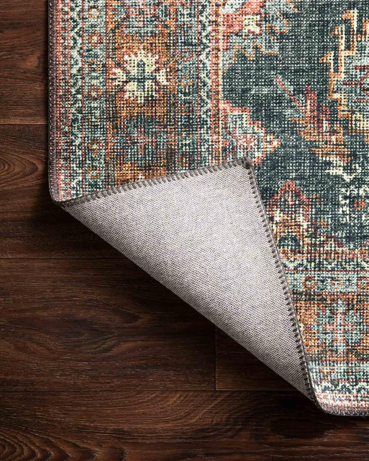 Rug corner with visible underside, showing teal, rust, and beige geometric weave