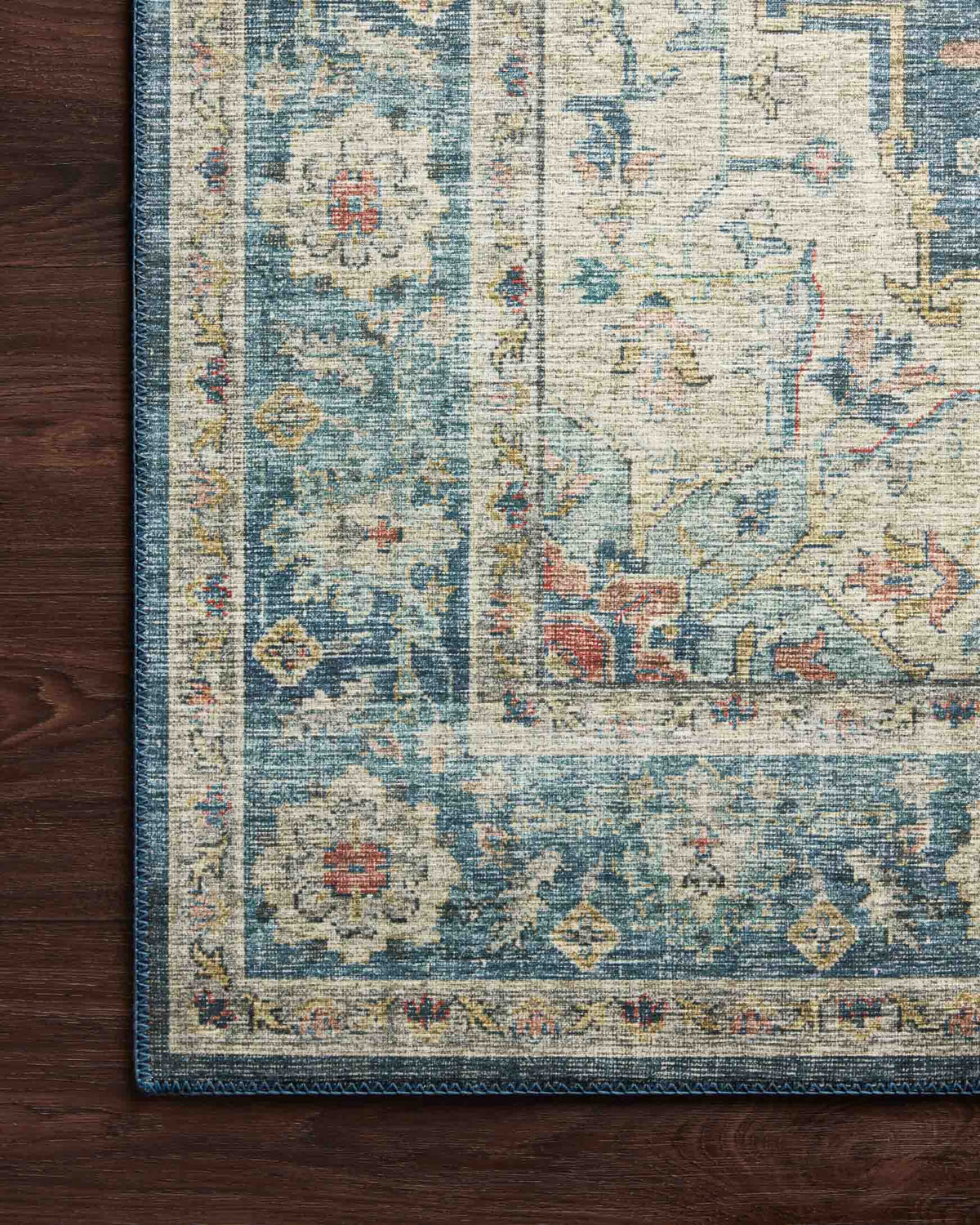 Ocean-blue rug corner with distressed pattern on dark wood flooring