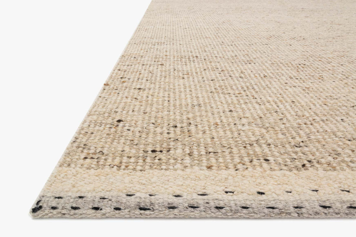 Natural hand-woven rug corner with textured weave and stitched border edging
