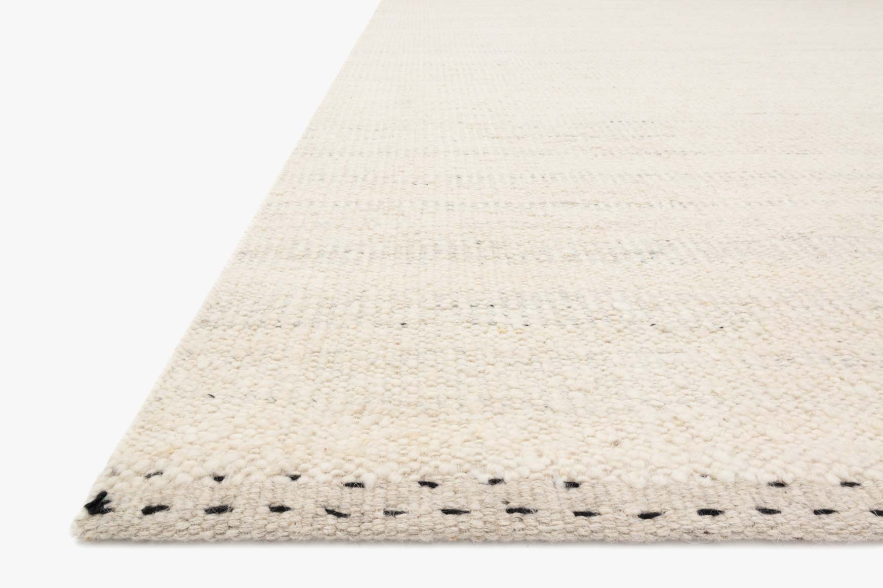 Light beige rug corner with black stitched border and textured flatweave