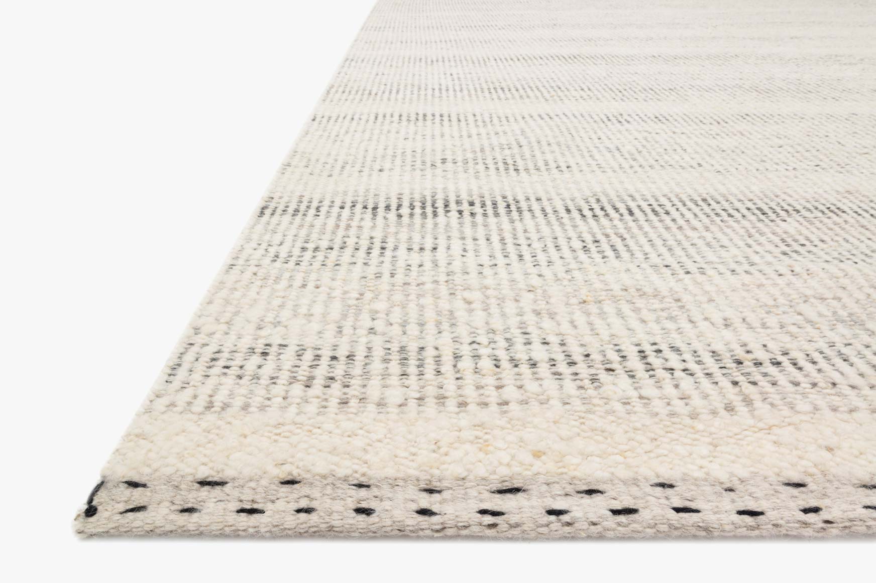 Light smoke-gray and cream rug corner with black stitched edge detail