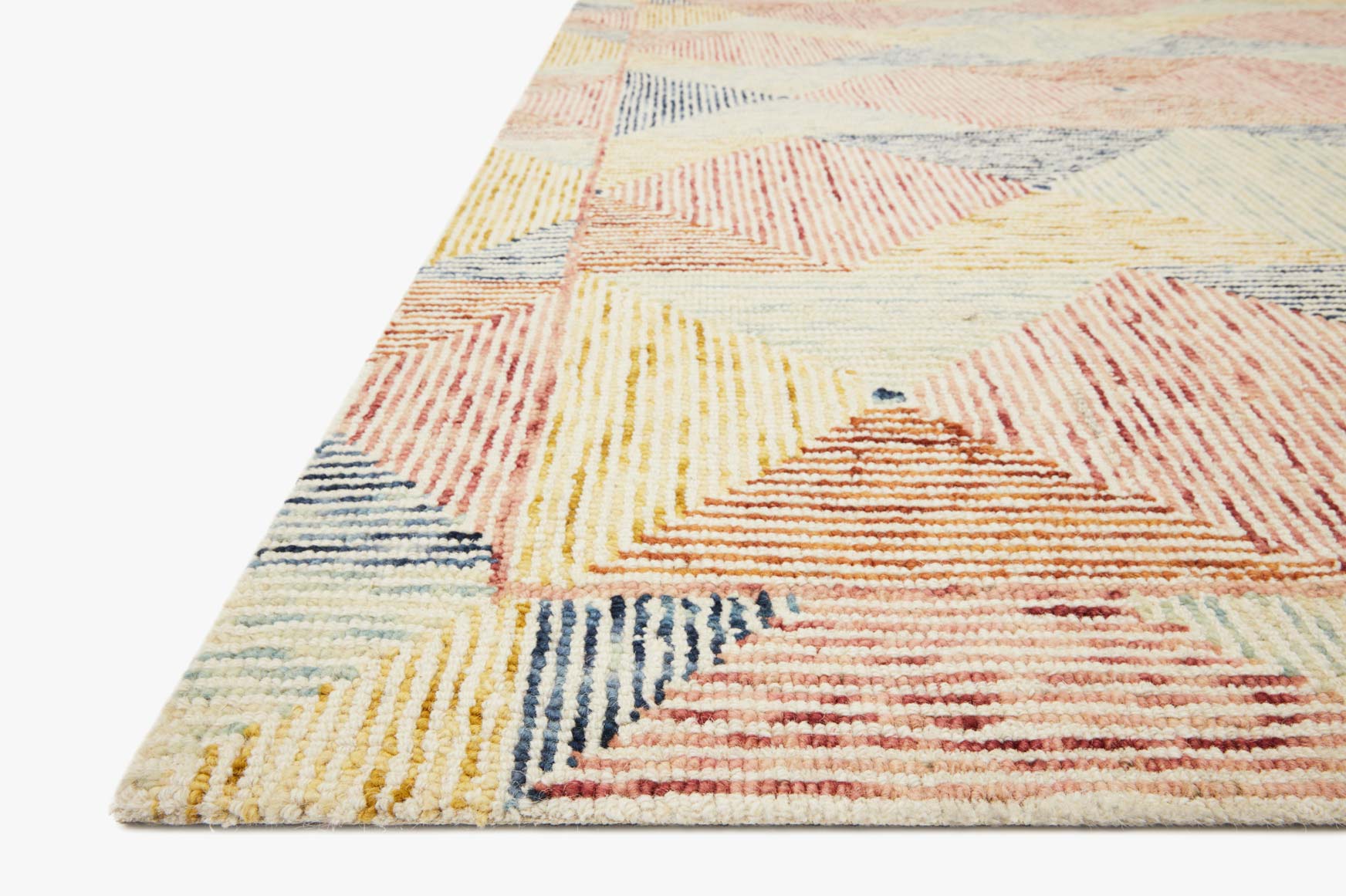 Close-up of hooked rug showing zigzag and diamond motif in ivory, coral, blue, and yellow
