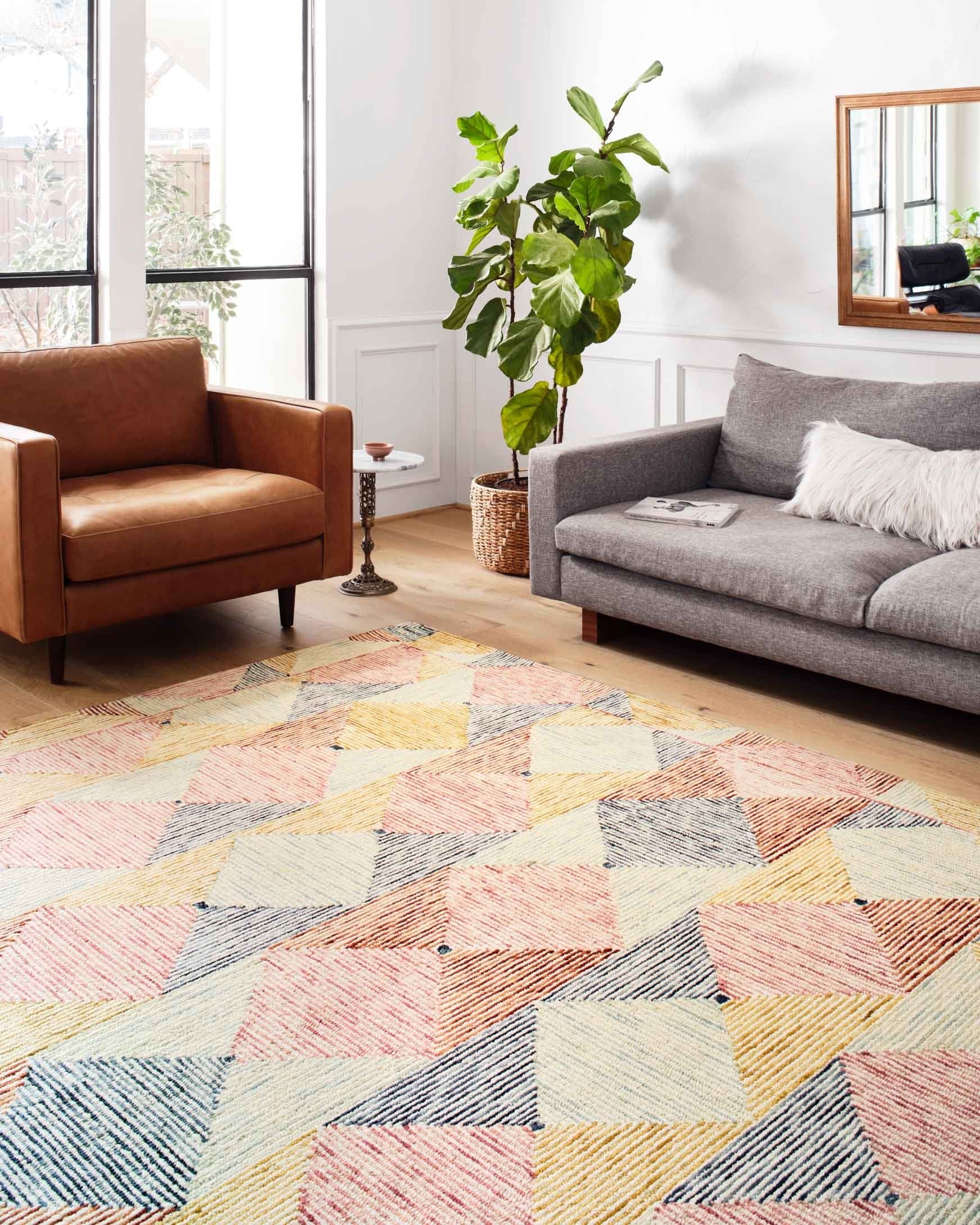Multicolor geometric hooked rug on floor with diamond shapes in blue, coral, and ivory